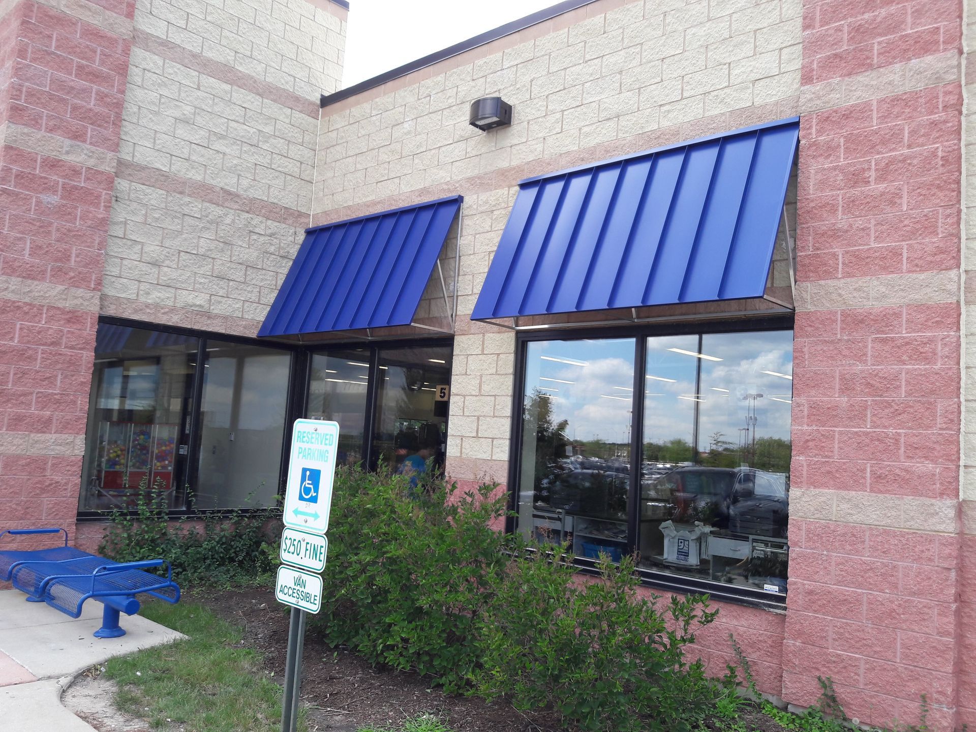 A brick building with a blue awning on the windows.