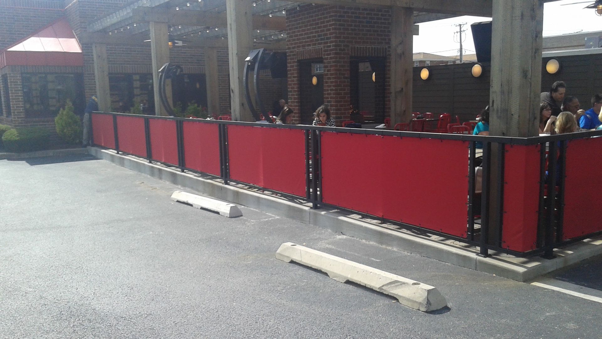 A red fence surrounds a parking lot in front of a restaurant