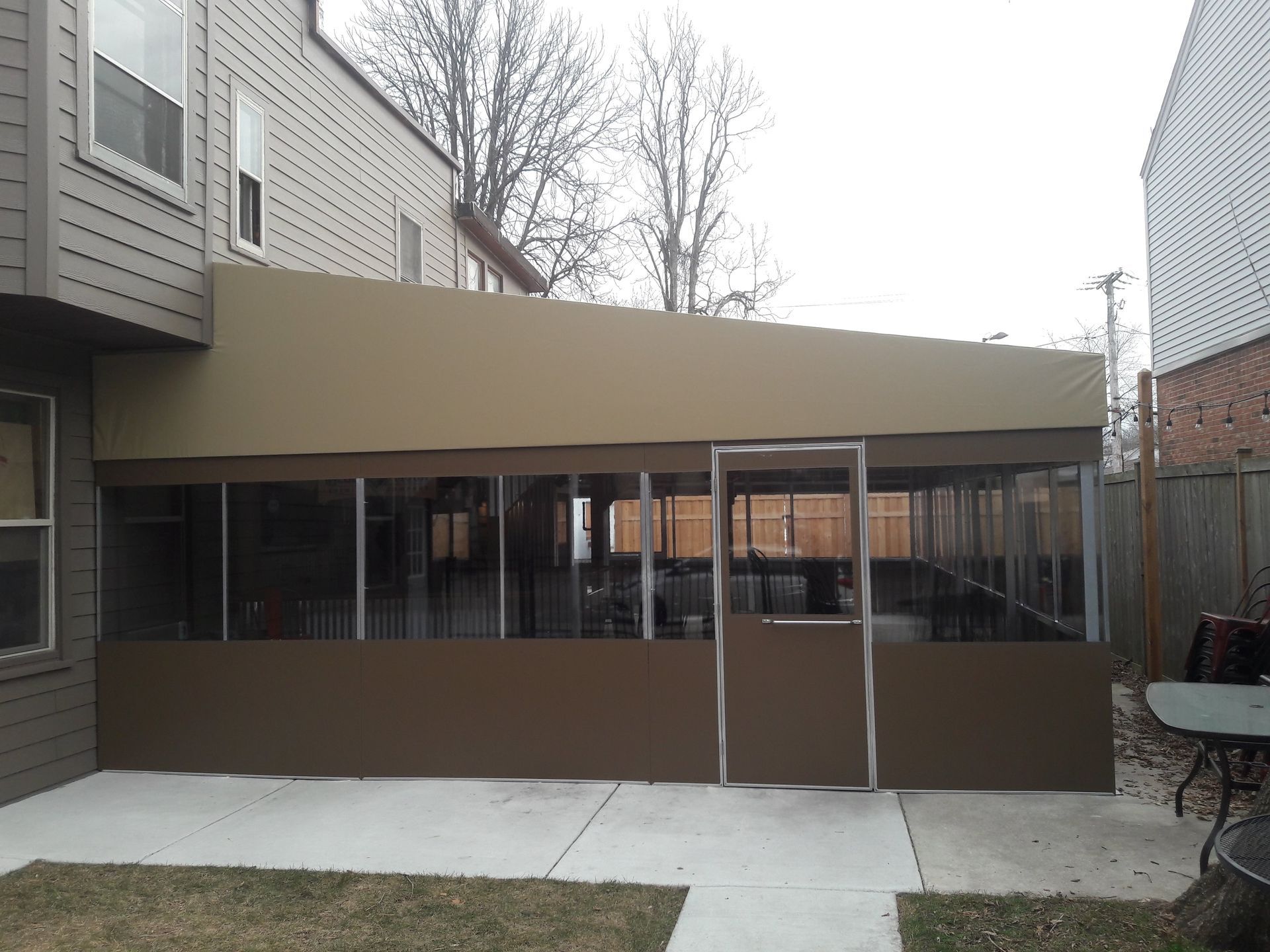 There is a screened in porch in the backyard of a house.