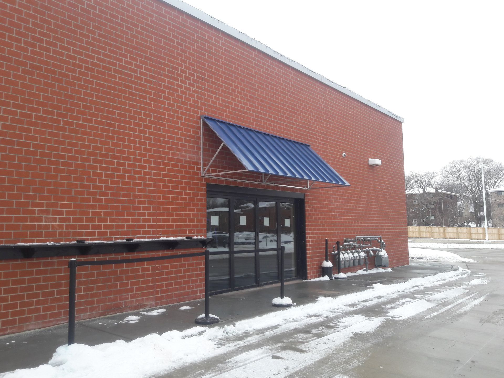 A red brick building with a blue awning over the door.