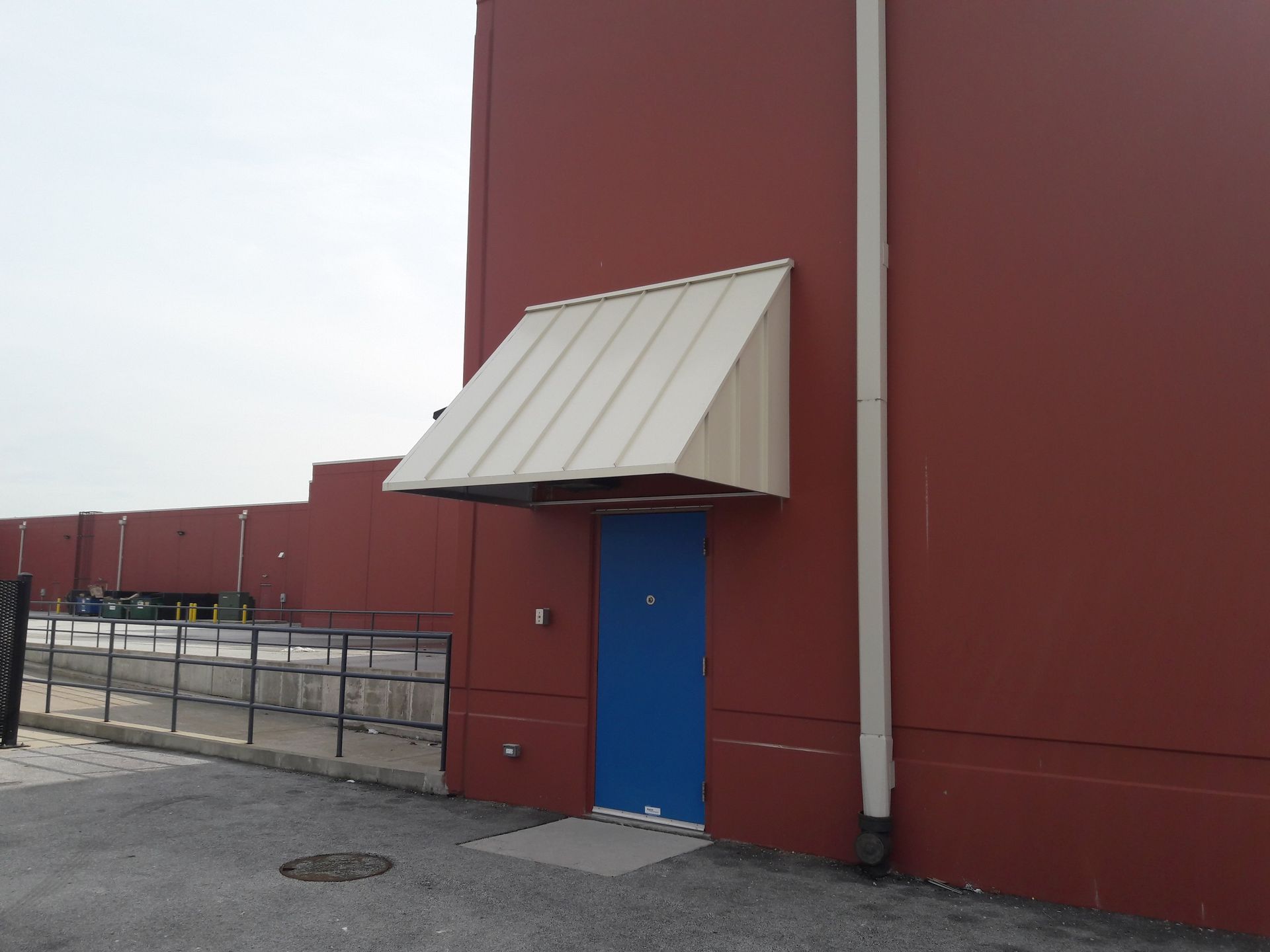 A red building with a white awning over a blue door