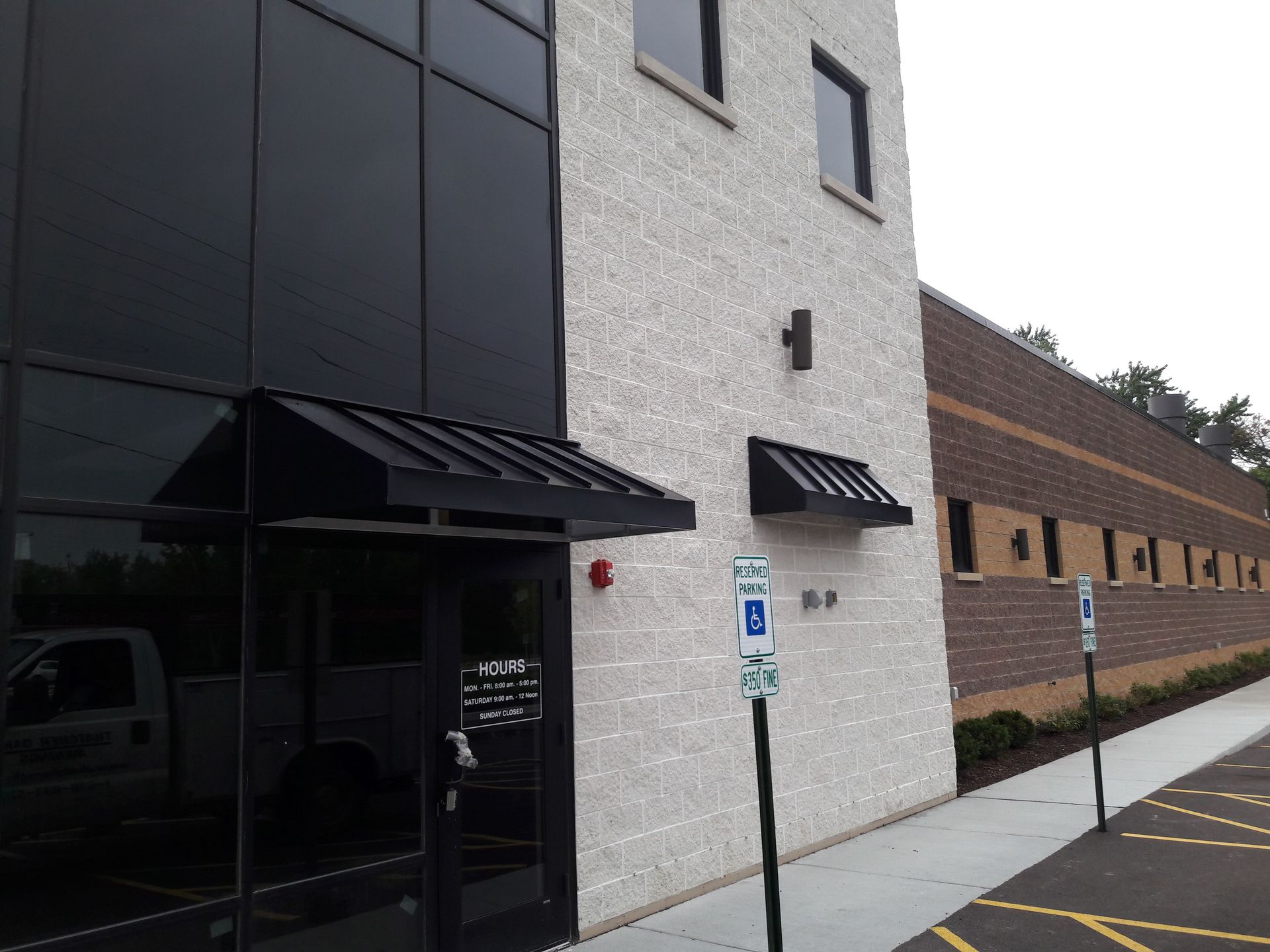 A white building with a black awning and a handicapped parking sign