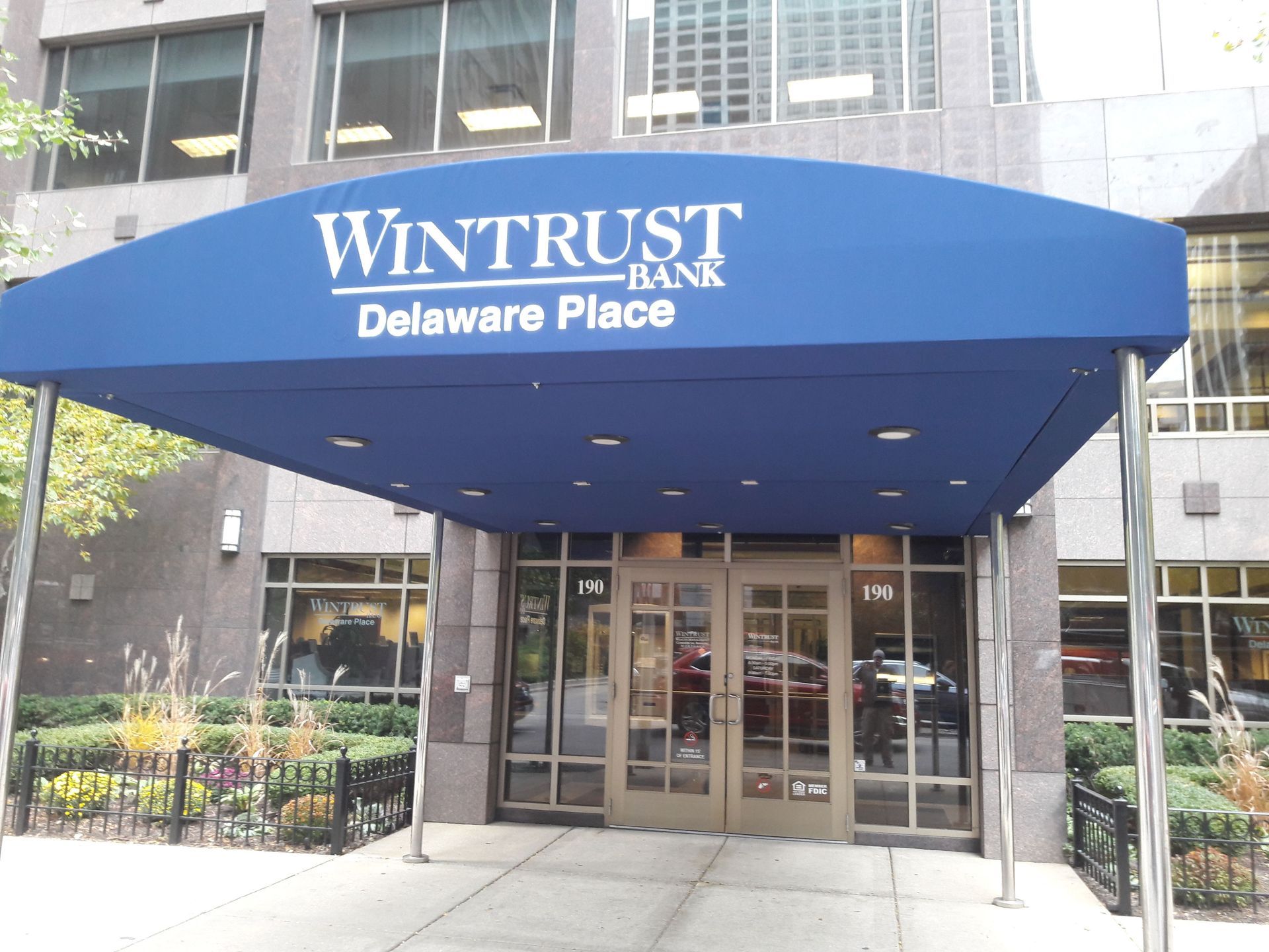 A building with a blue awning that says wintrust bank delaware place