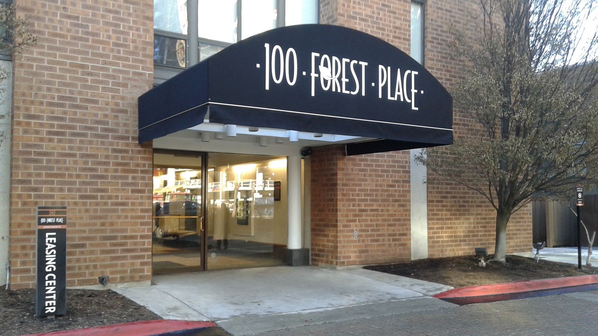 A brick building with a black awning that says 100 forest place