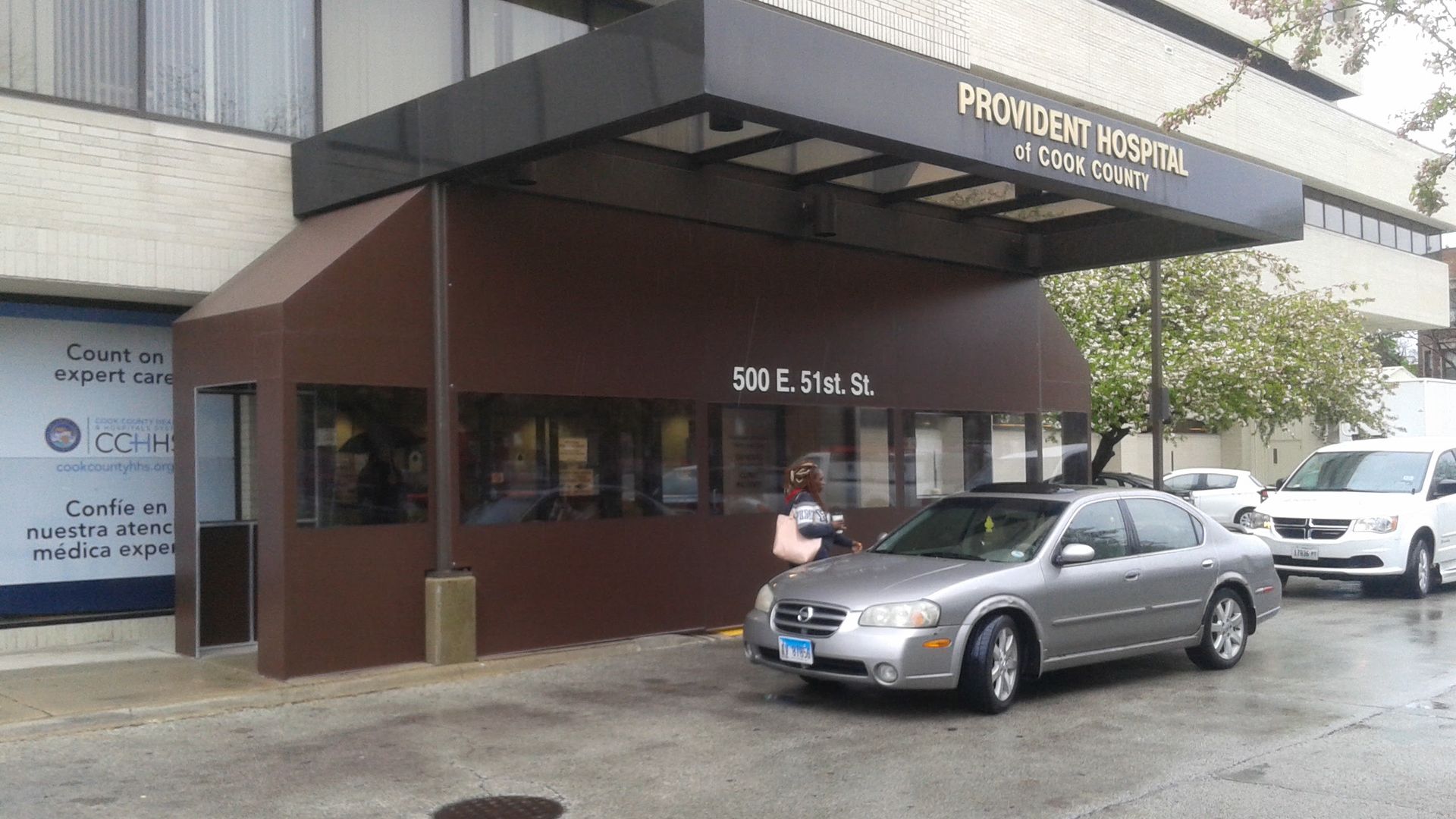 A silver car is parked in front of a building with a brown awning.