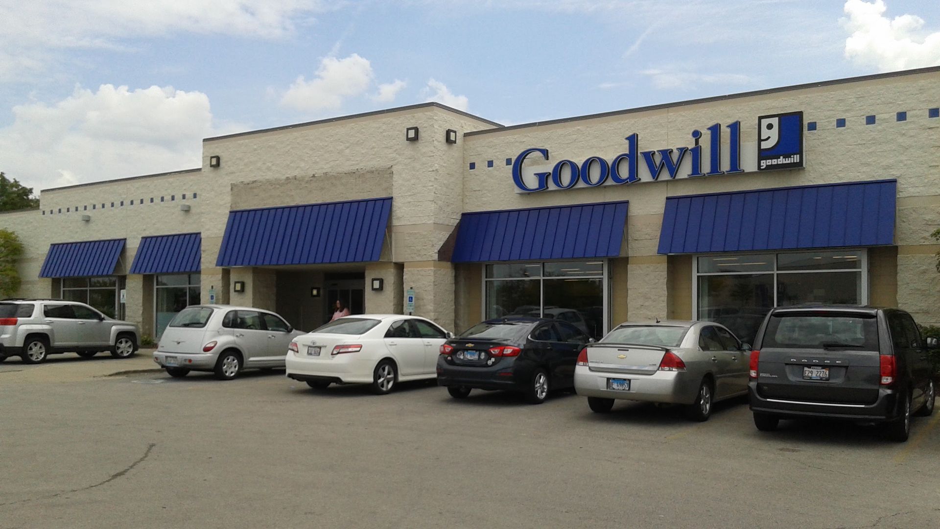 A goodwill store with cars parked in front of it