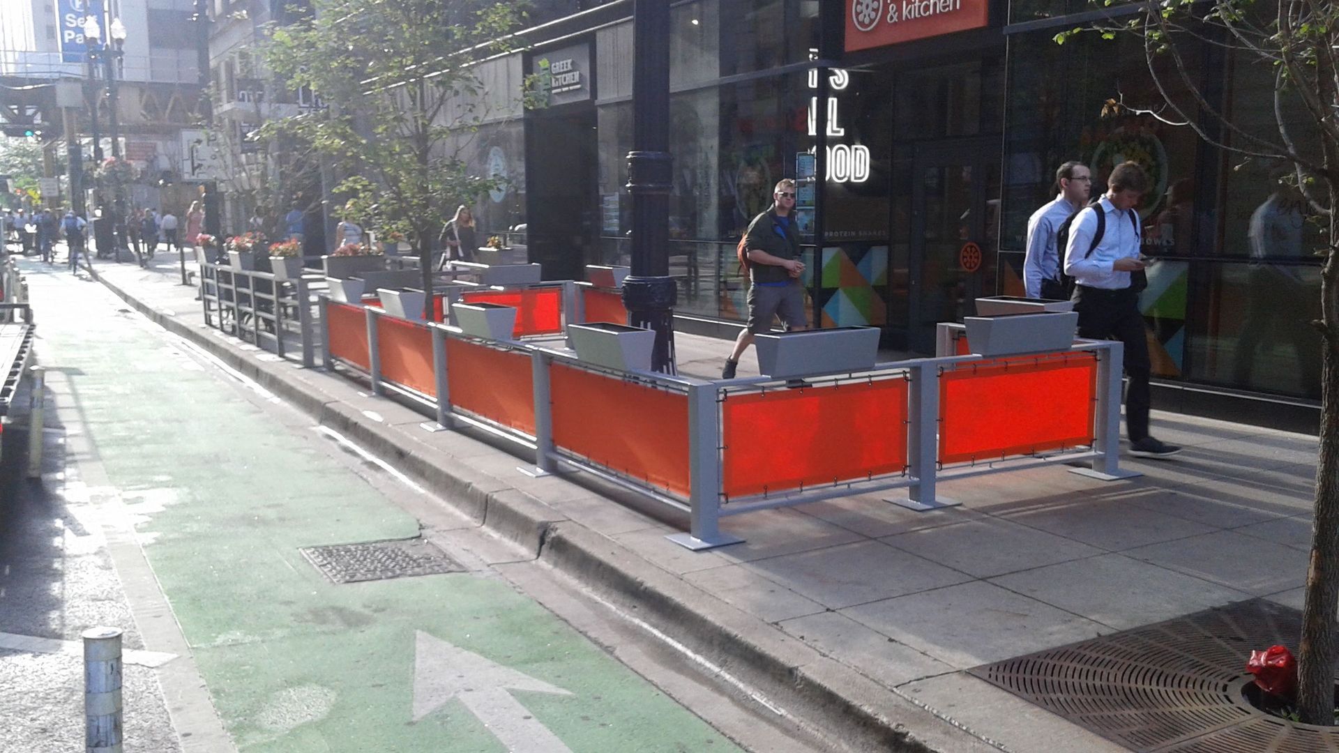A row of orange barriers on a sidewalk next to a green arrow