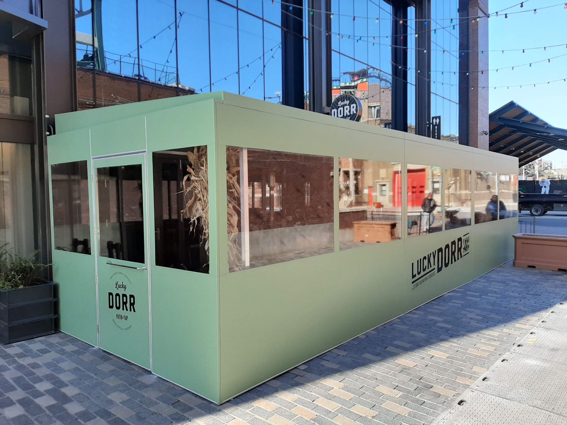 A green building with a lot of windows is sitting in front of a building.