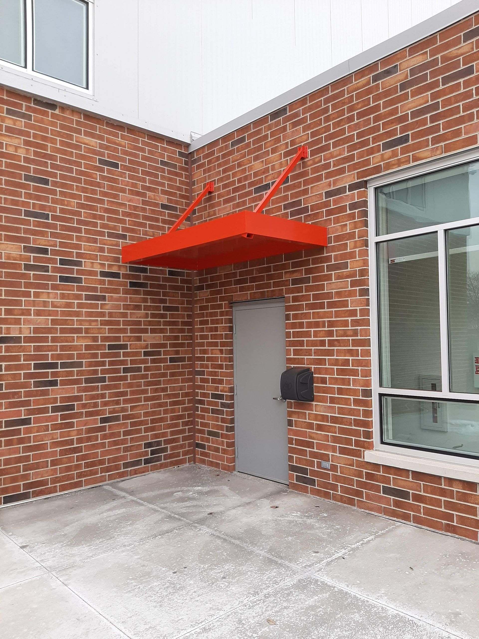 A red canopy is attached to the side of a brick building.