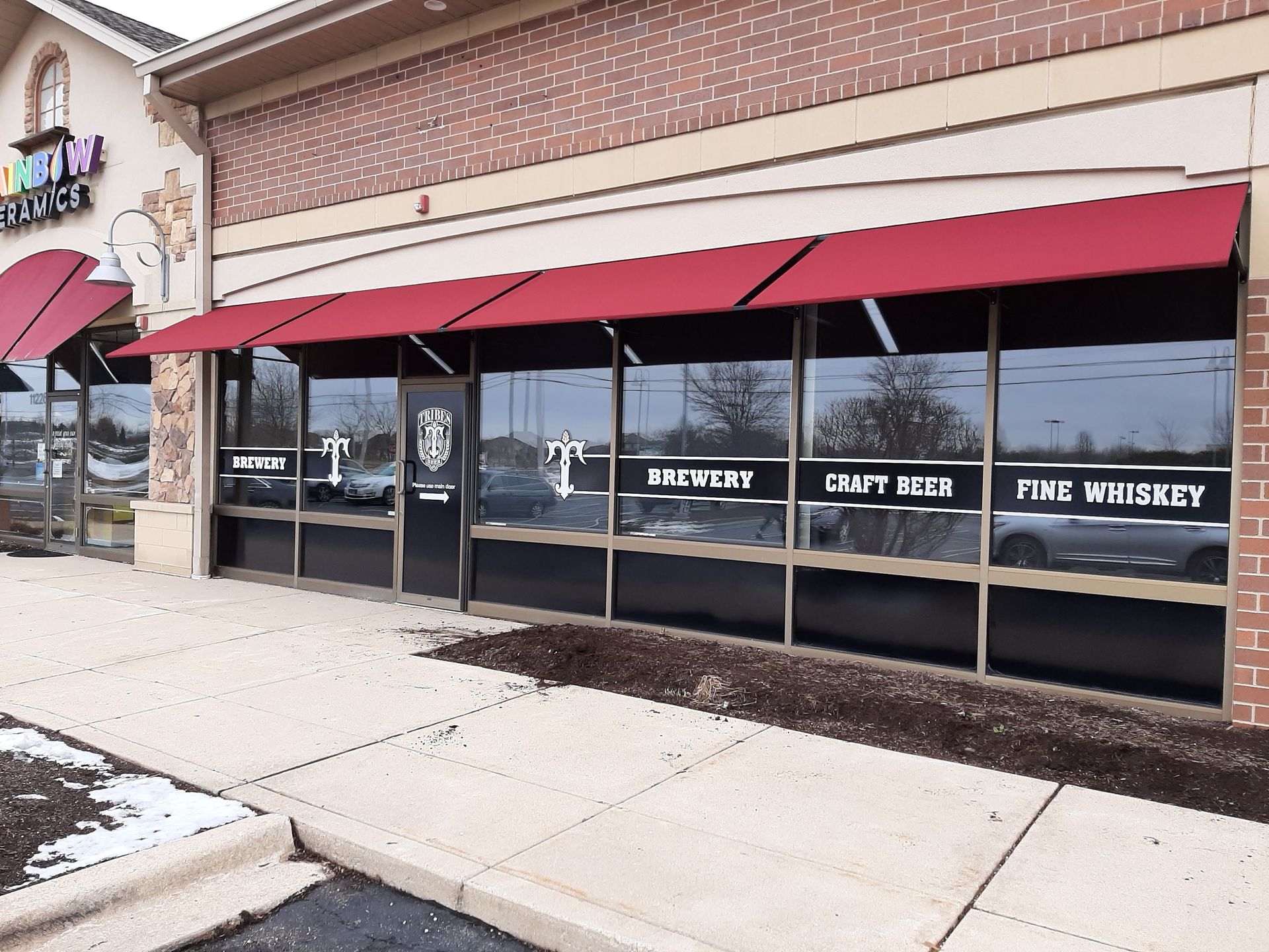 A store front with a red awning that says craft beer and fine whiskey