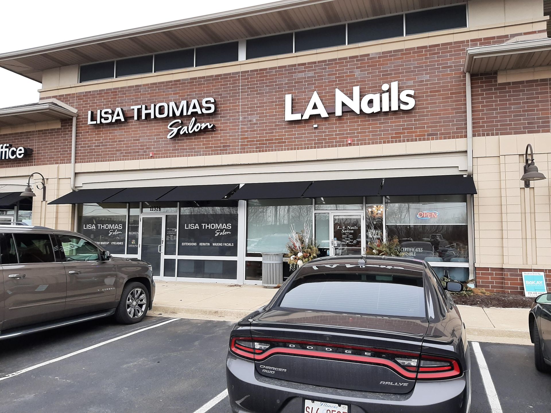 A car is parked in front of a la nails salon.