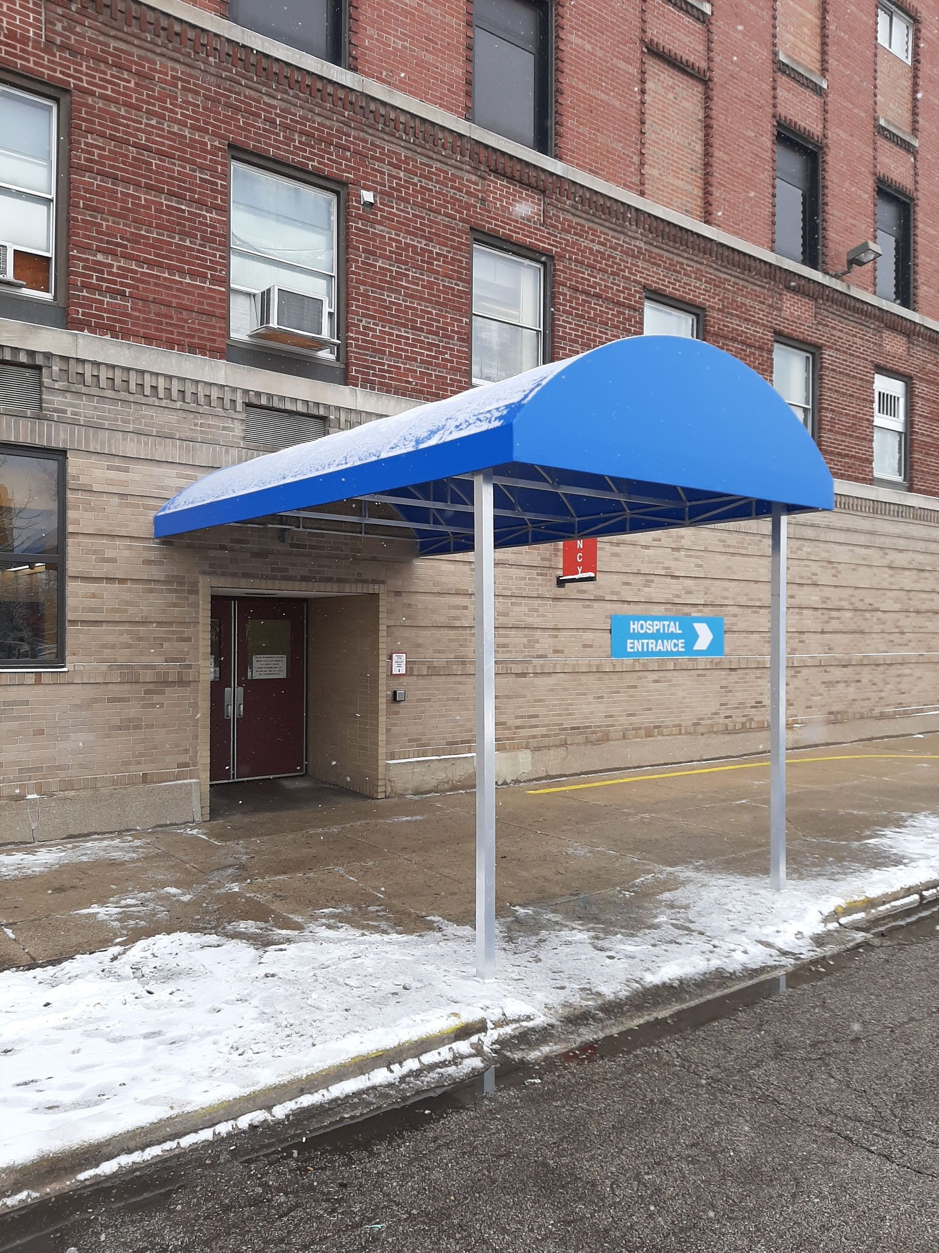 A brick building with a blue awning over the entrance
