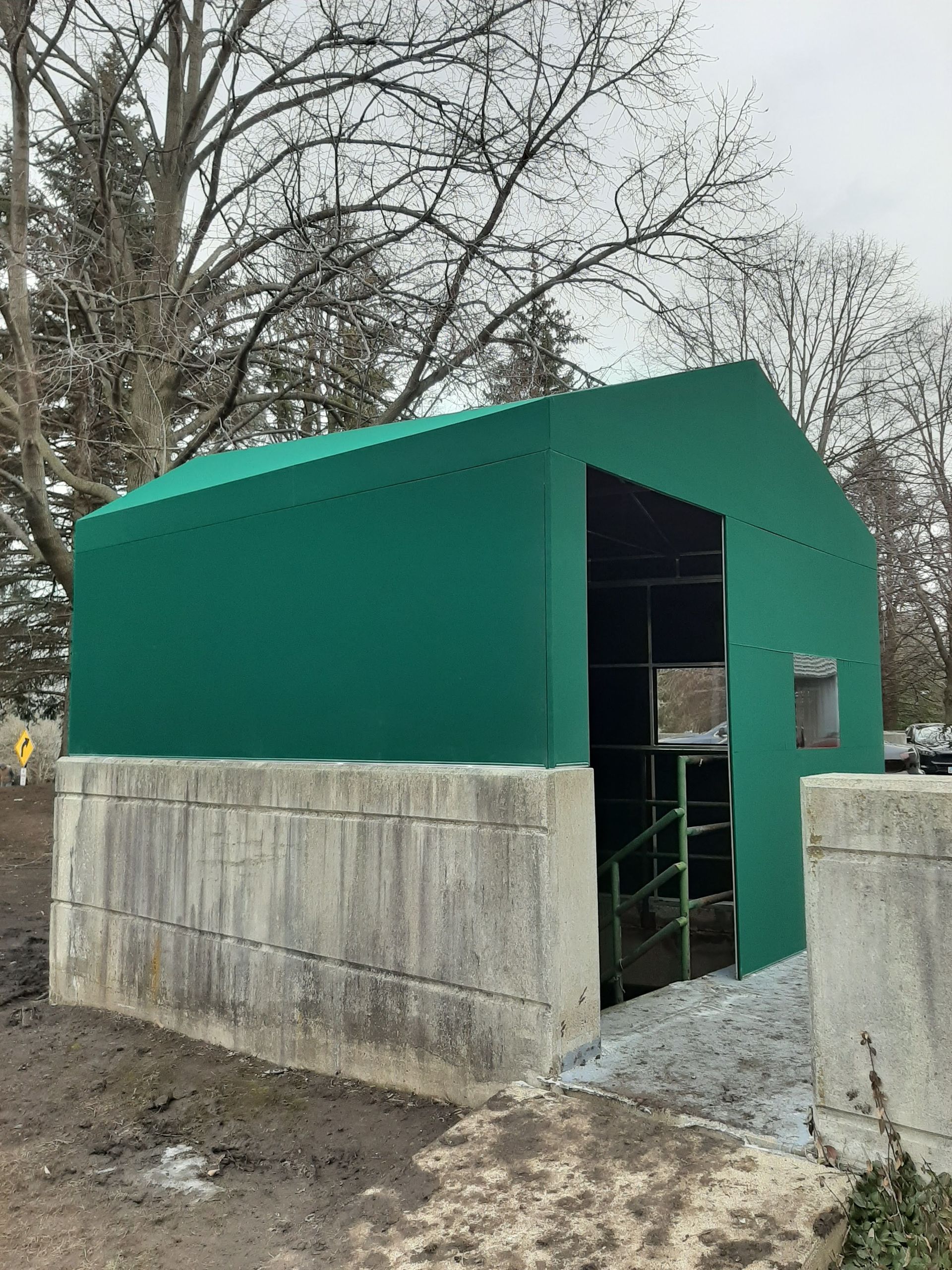 A green tent is sitting on top of a concrete wall.