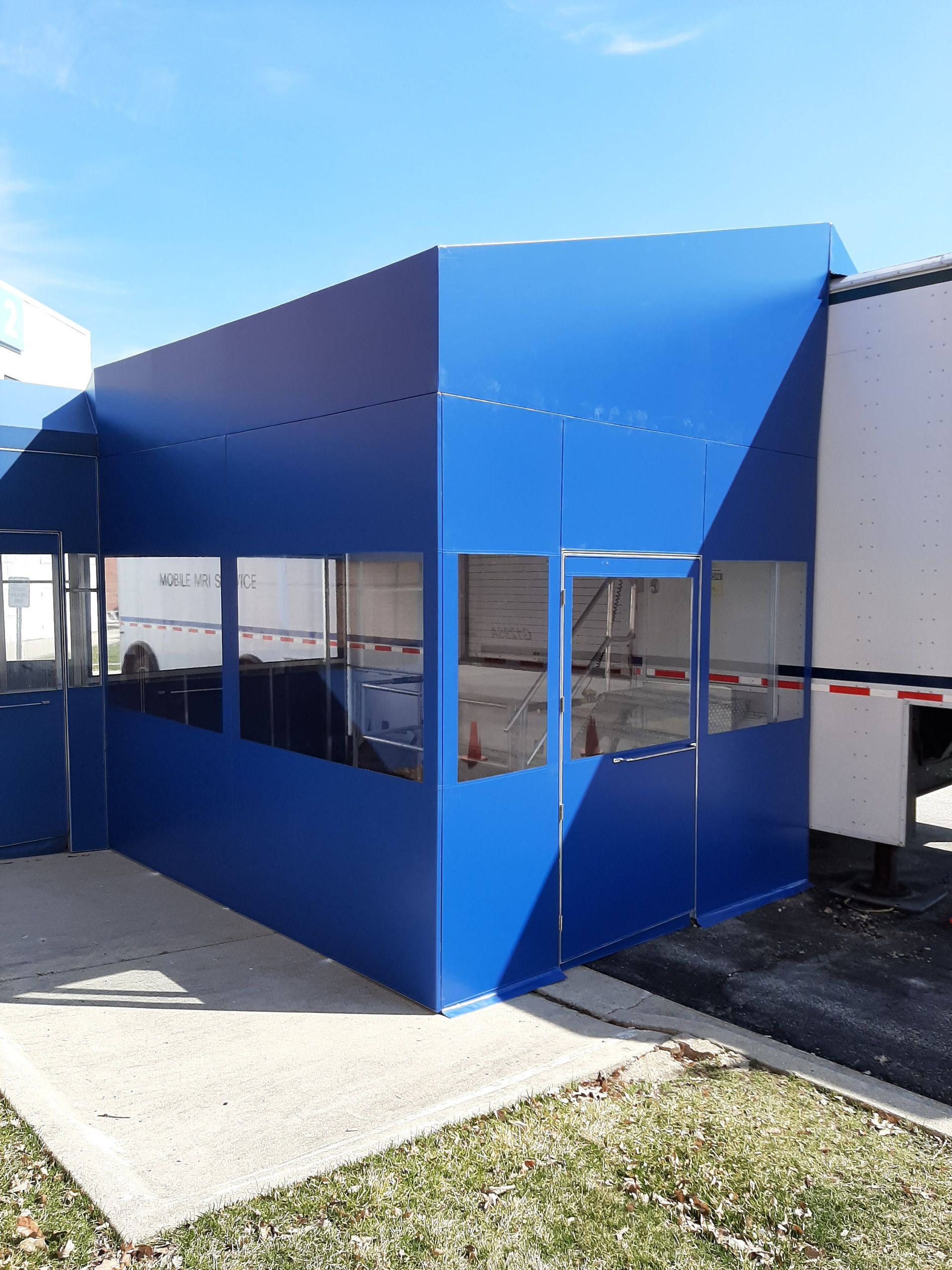 A blue building with a white trailer in the background