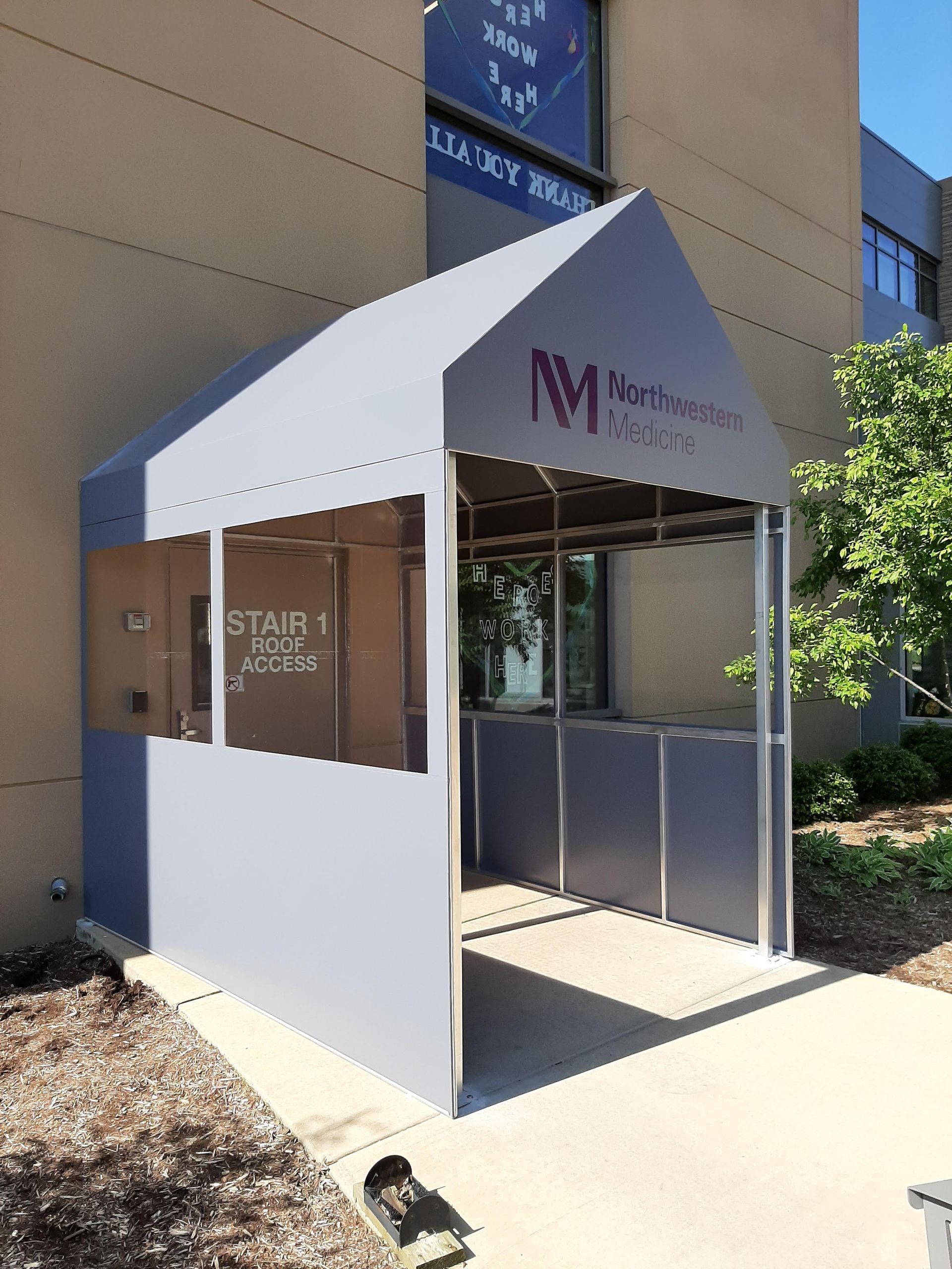 A gray and white tent is sitting in front of a building.