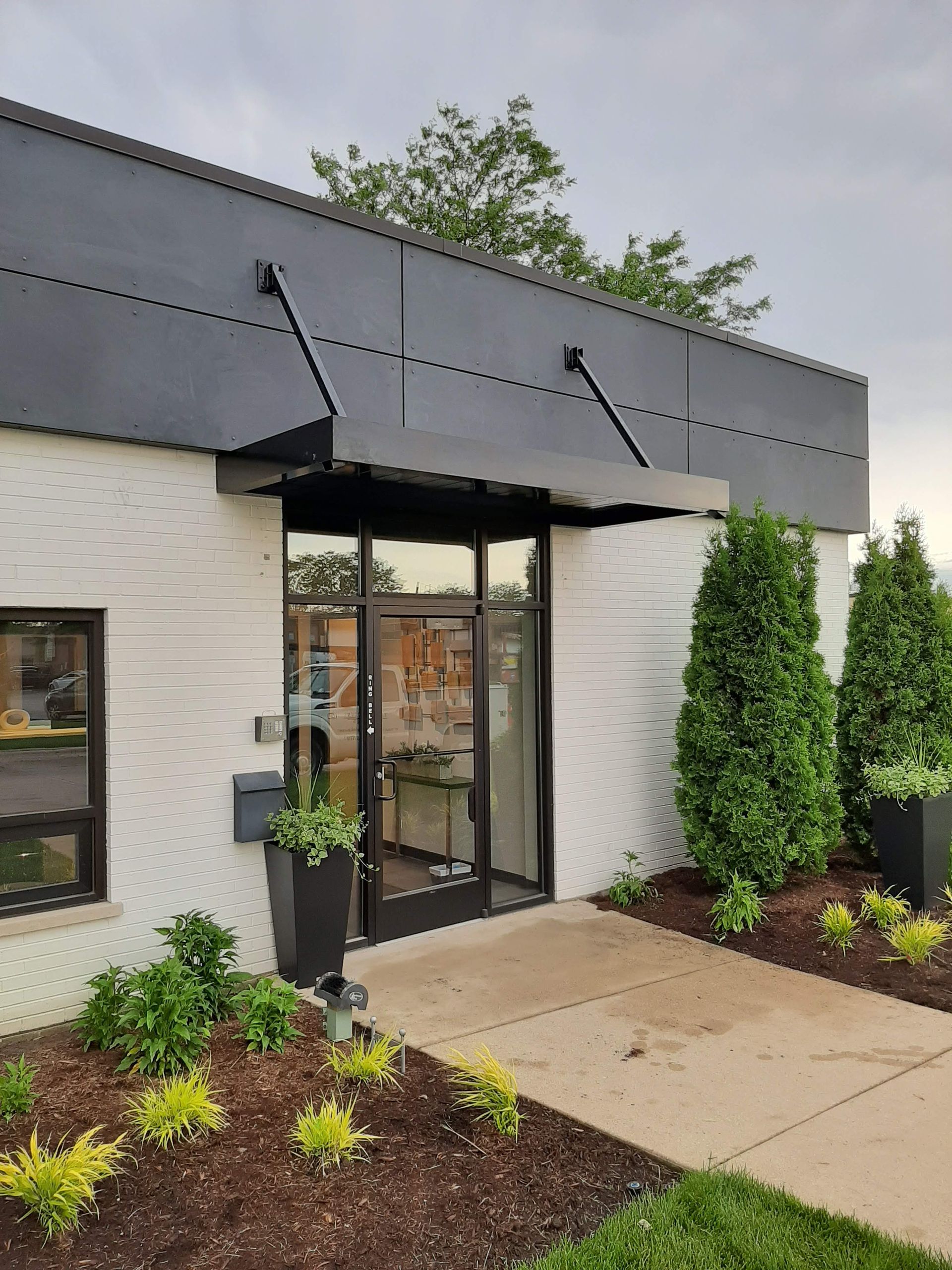 A white building with a black awning over the door