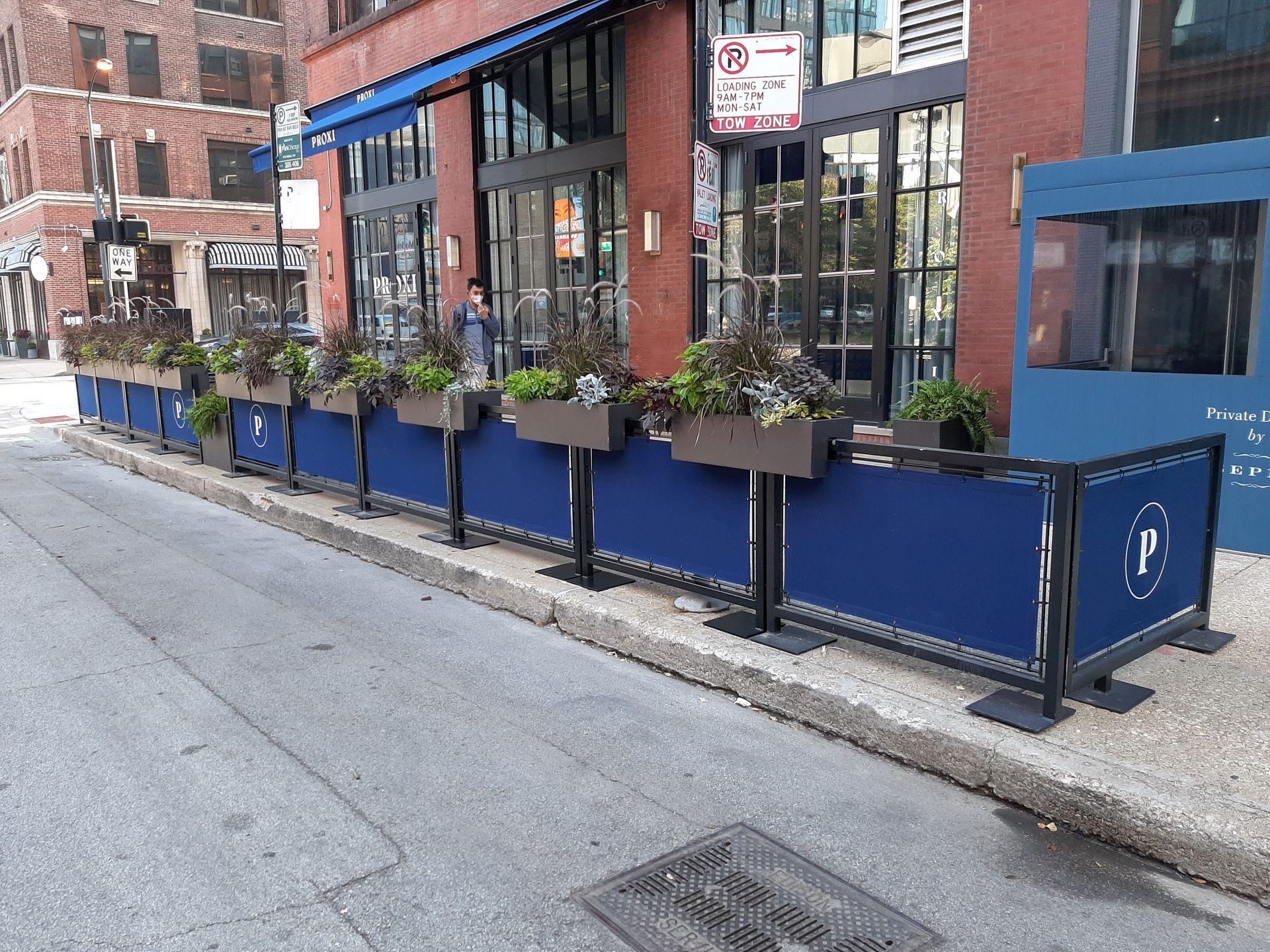 A row of blue planters on the sidewalk in front of a building.