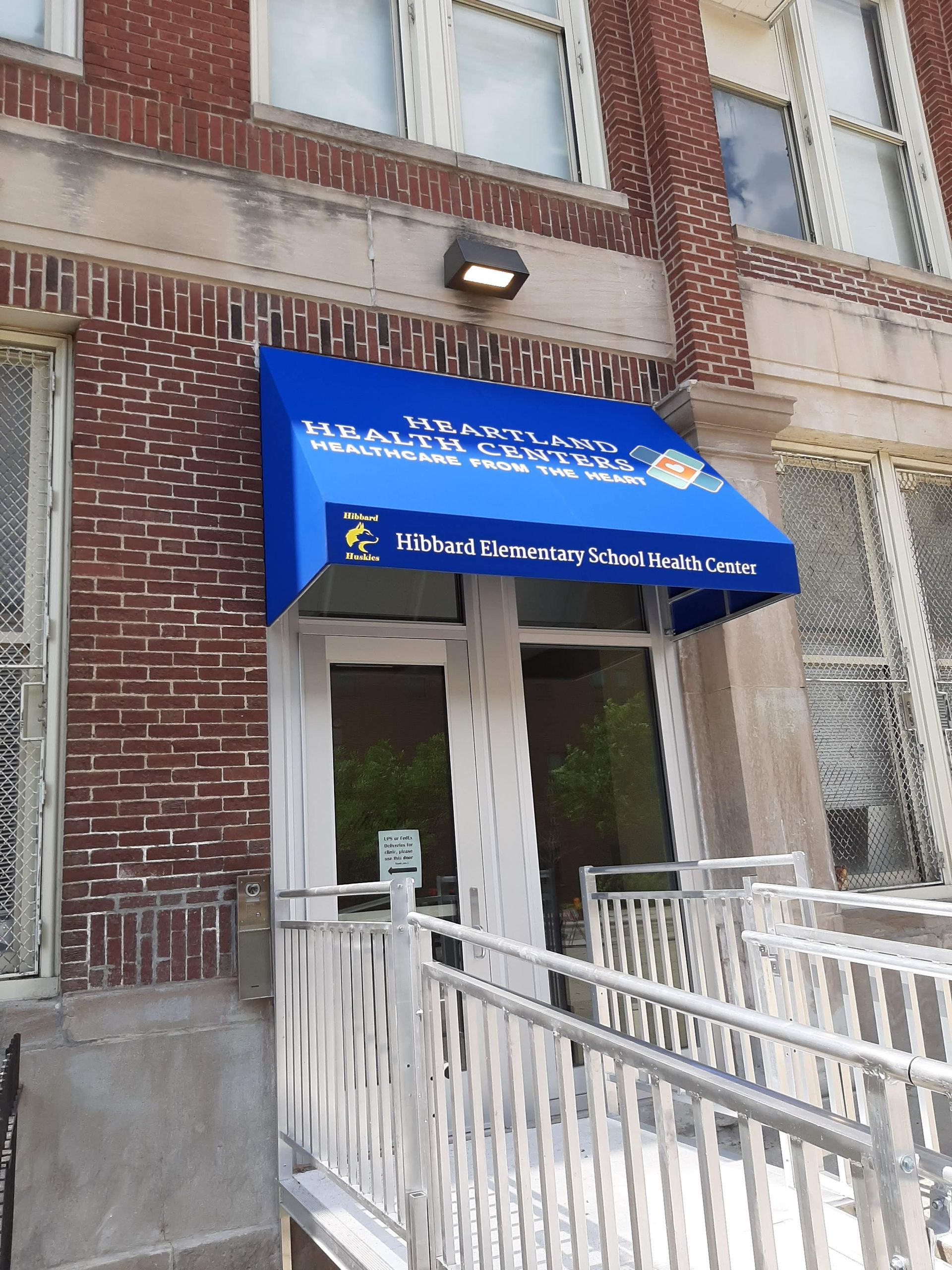 A brick building with a blue awning over the door