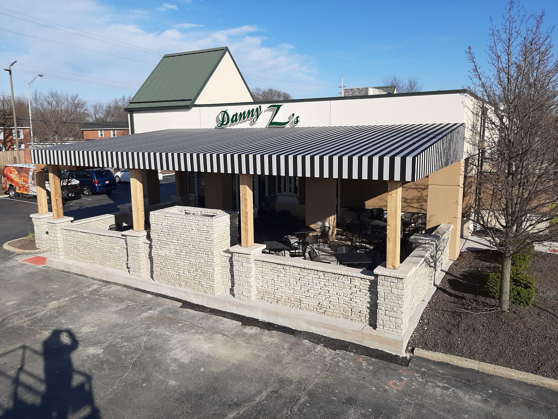 A restaurant with a striped awning on the side of it.