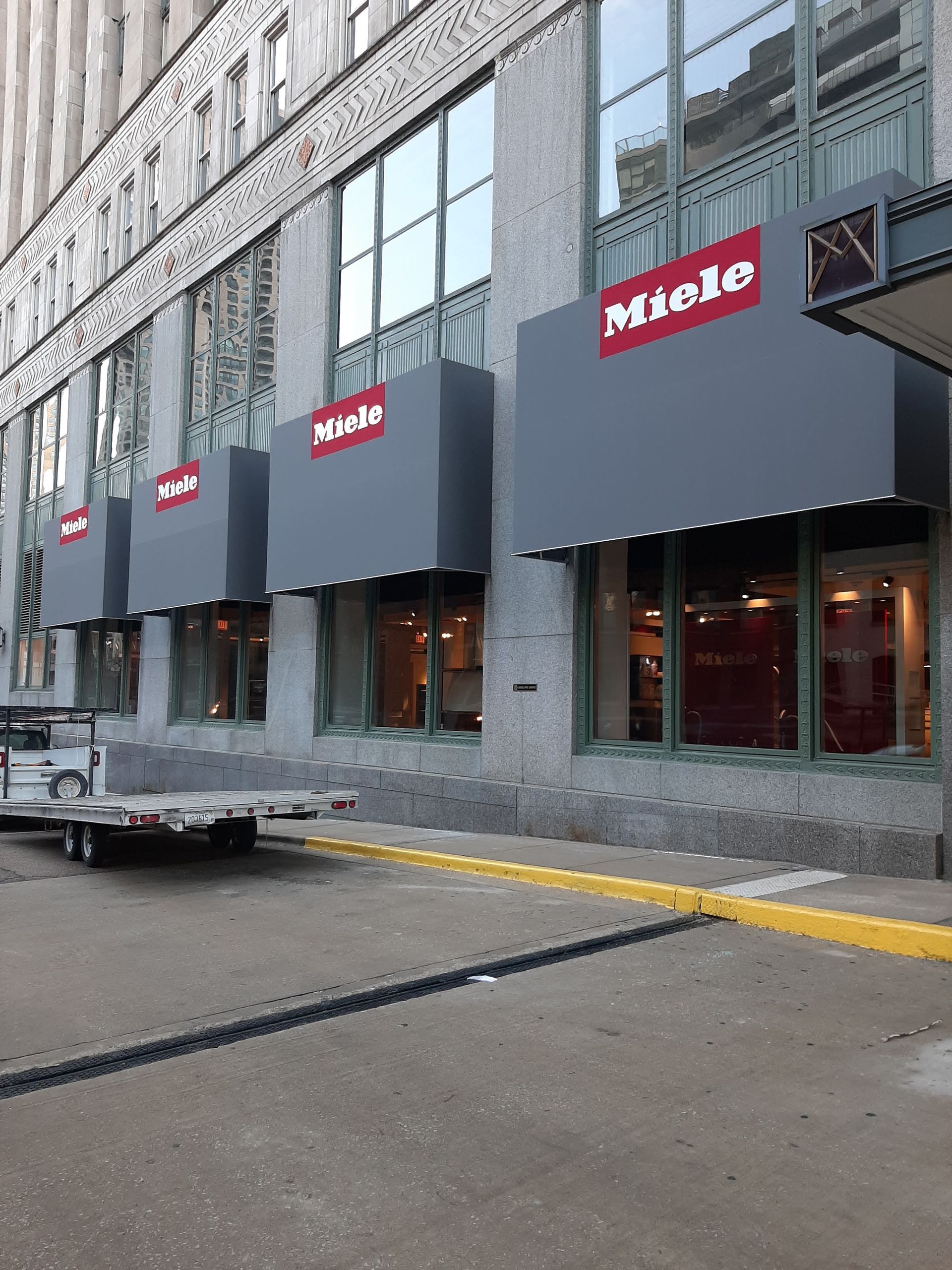 A truck is parked in front of a building that says miele