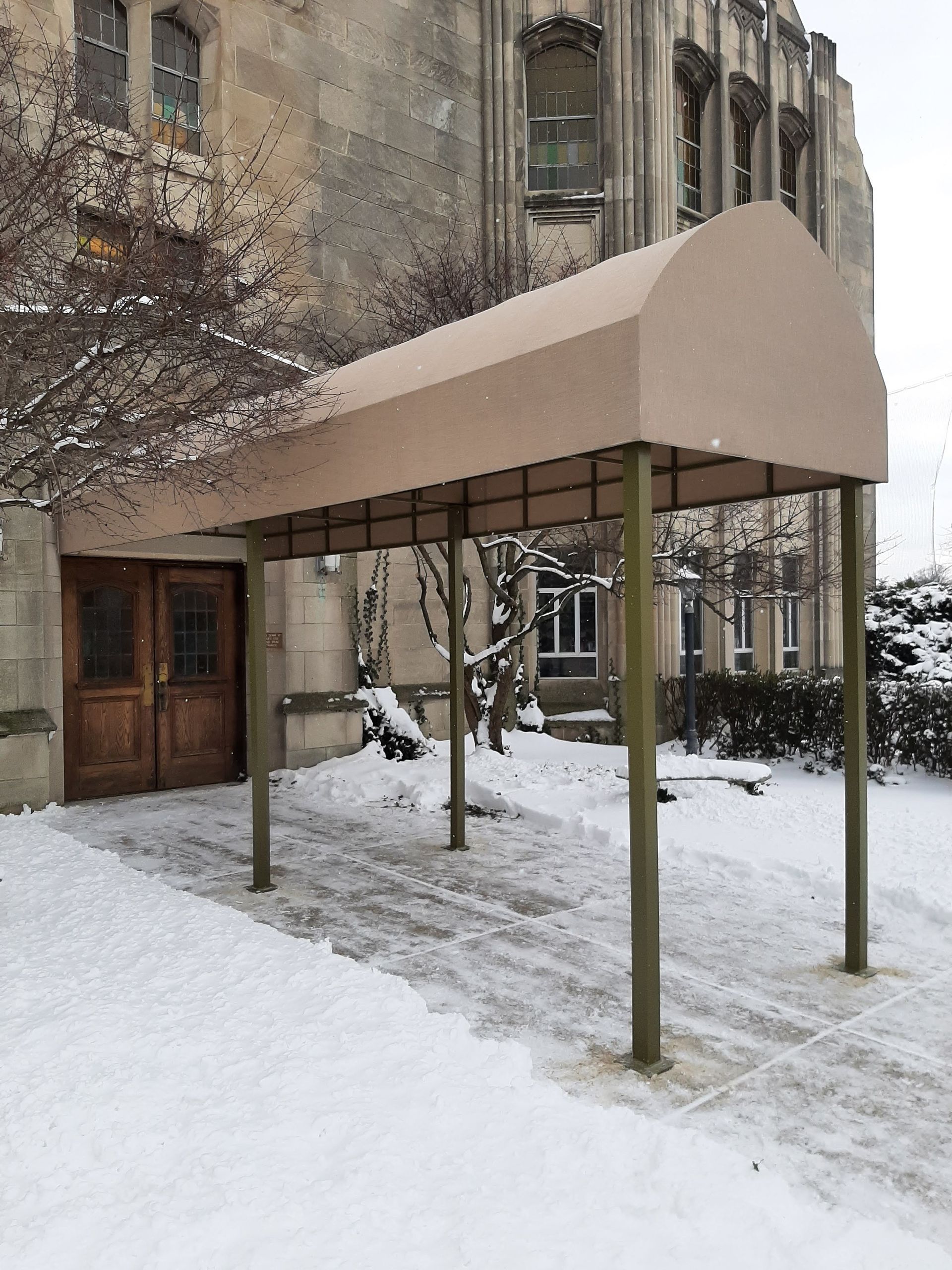 A canopy is sitting in front of a building in the snow