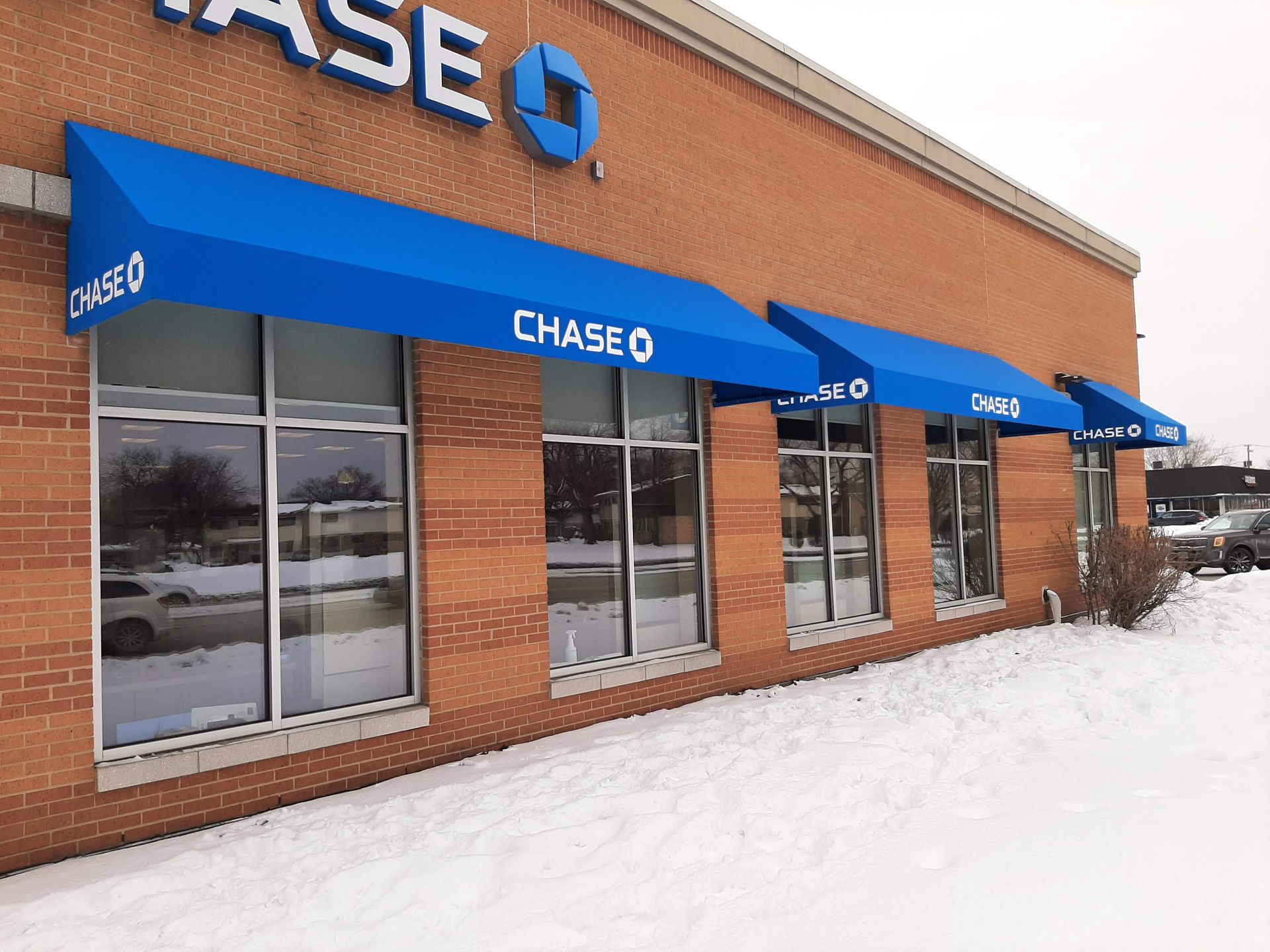 A chase bank building with a blue awning over the windows