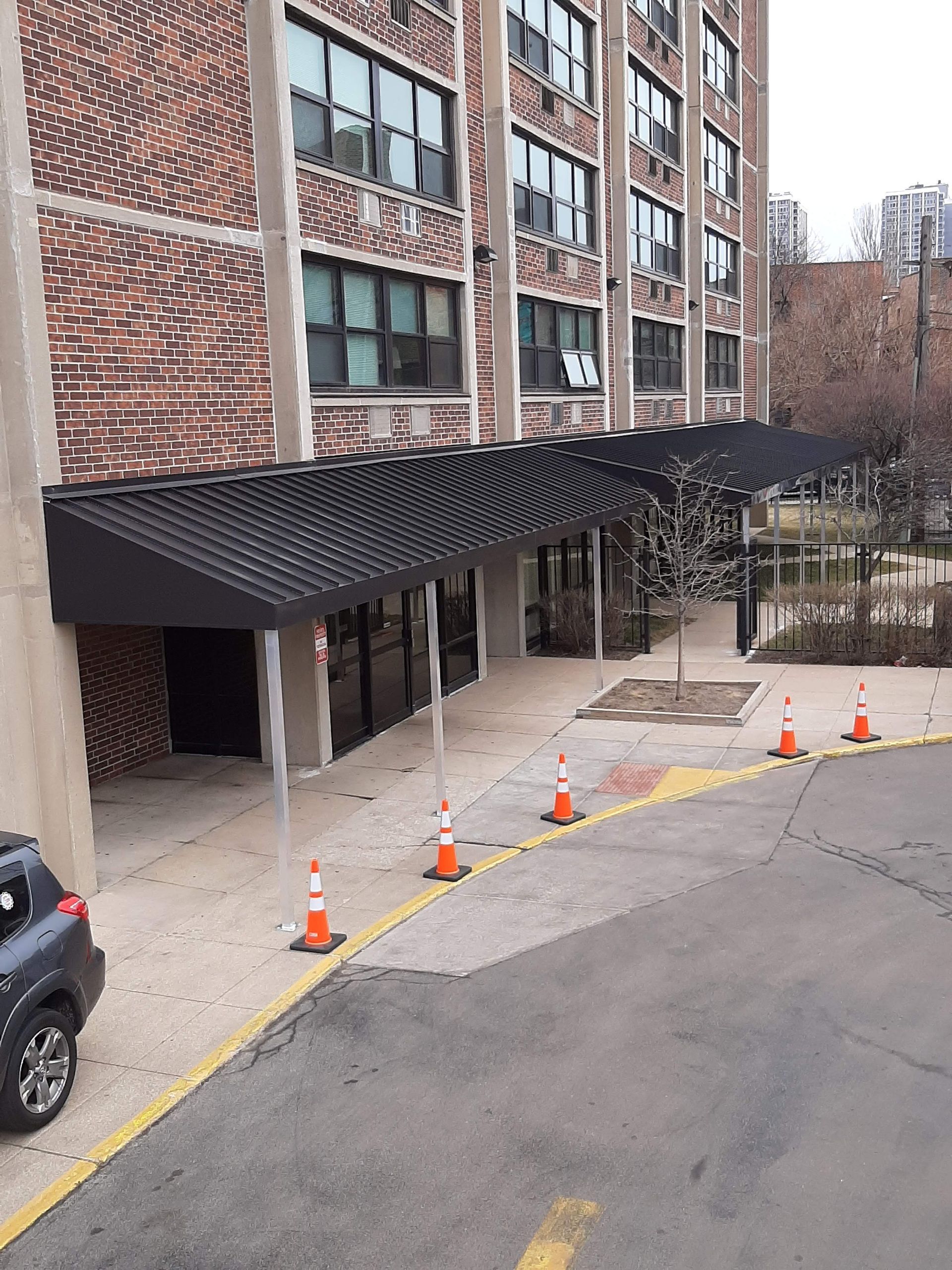 A car is parked in front of a building with a black awning