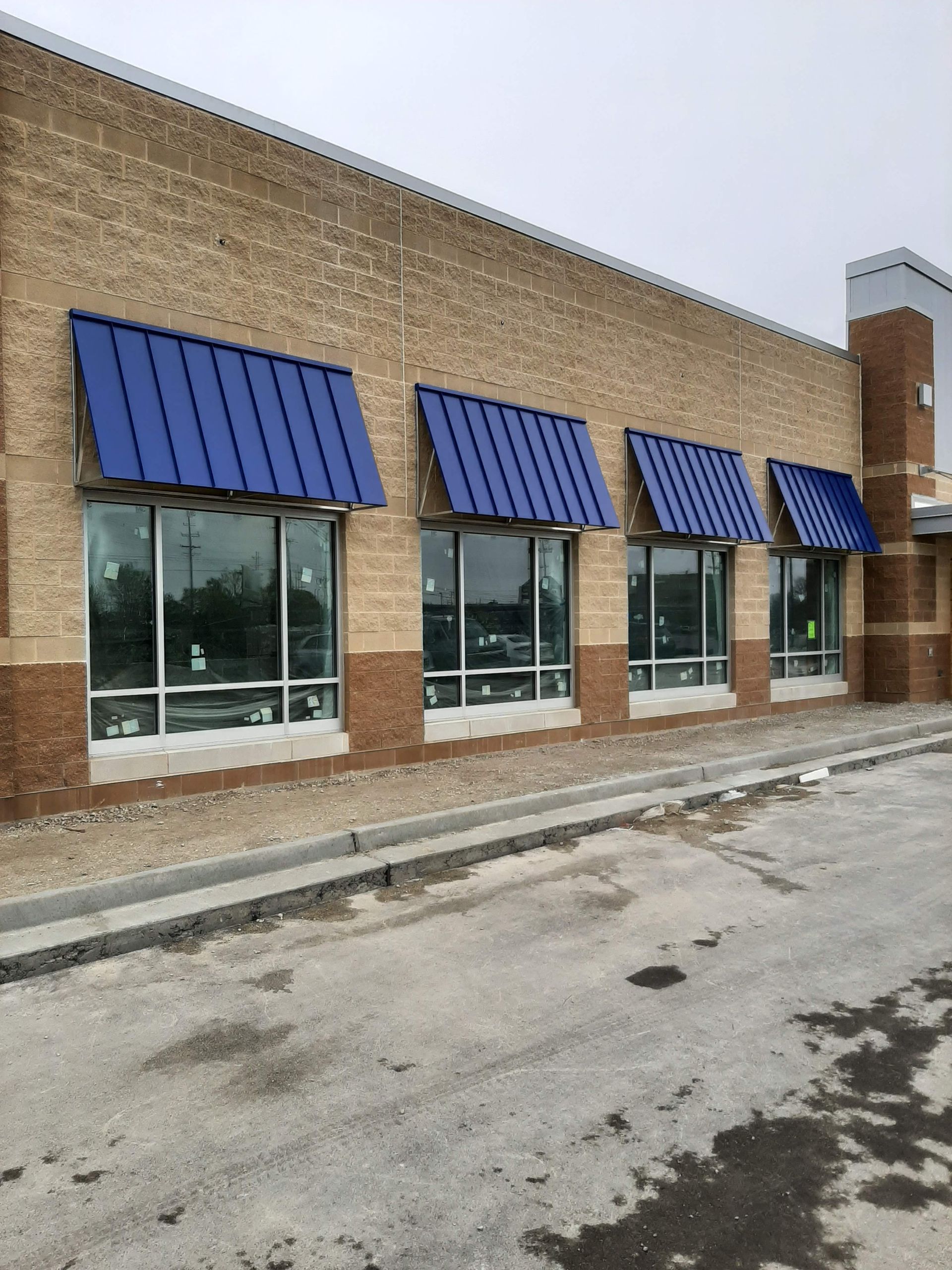 A brick building with blue awnings on the windows