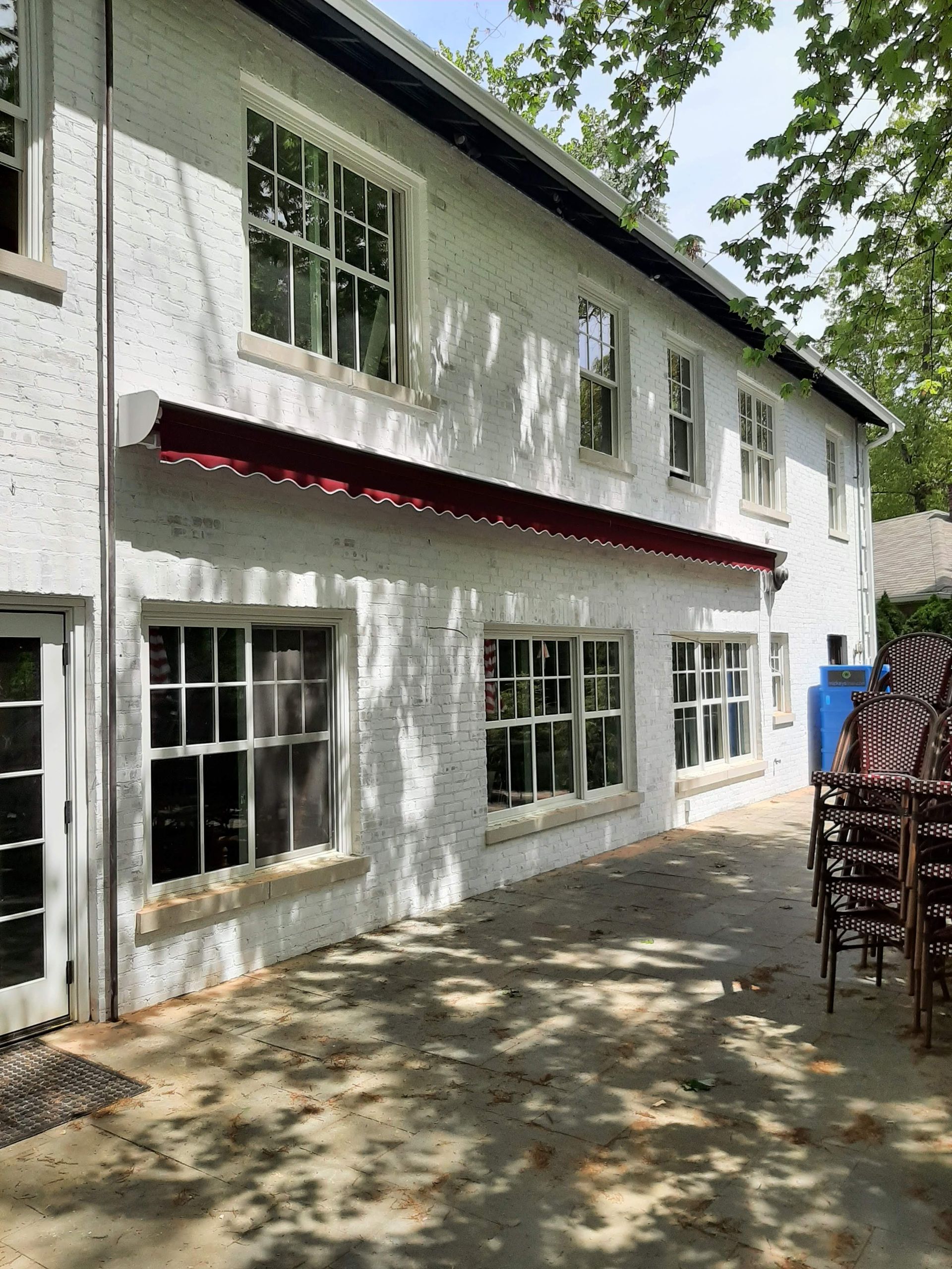 A white house with a red awning on the side of it.