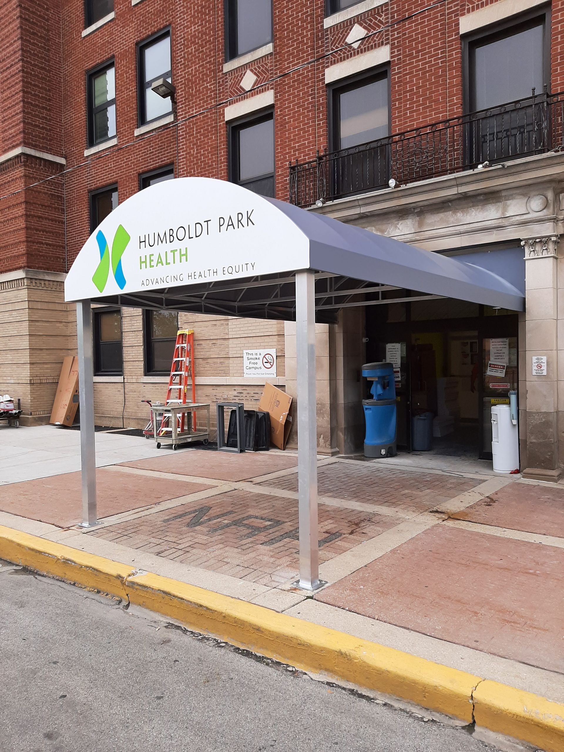 A canopy is being built in front of a brick building.