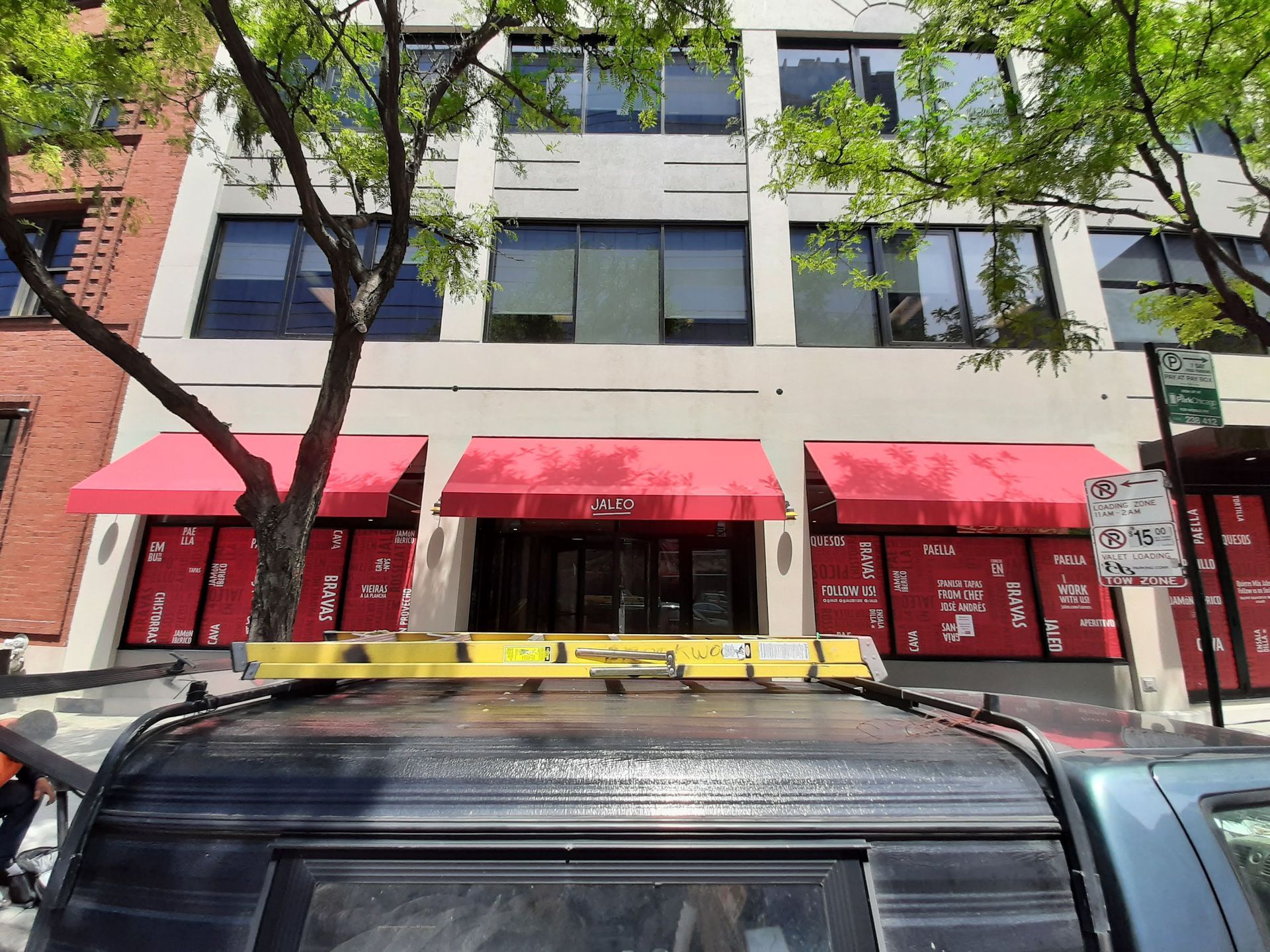 A car is parked in front of a building with red awnings