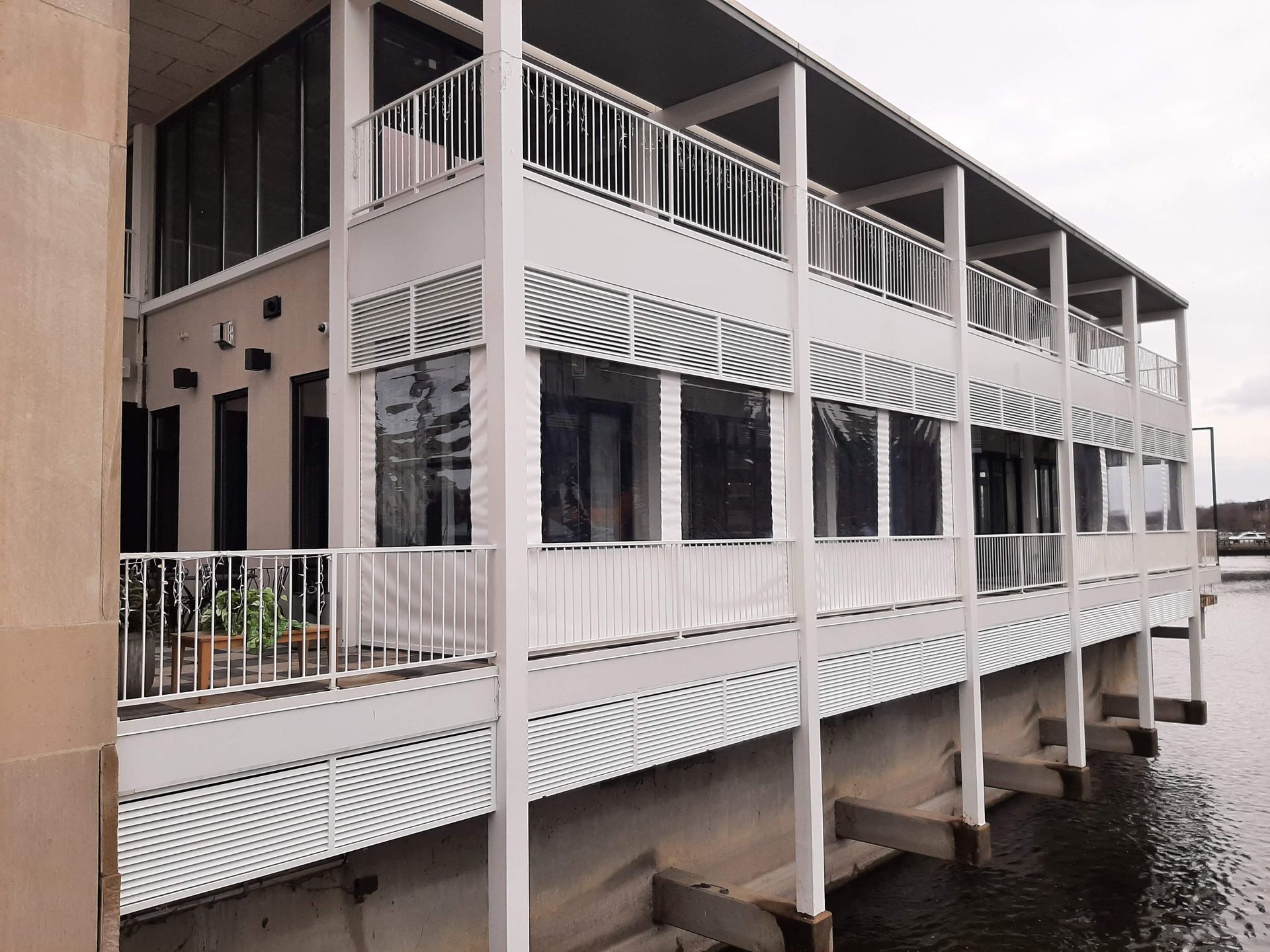 A large white building with a balcony overlooking a body of water.