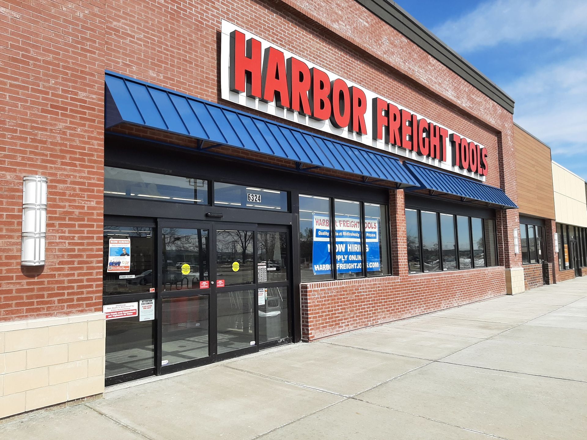 The front of a harbor freight tools store with a blue awning.