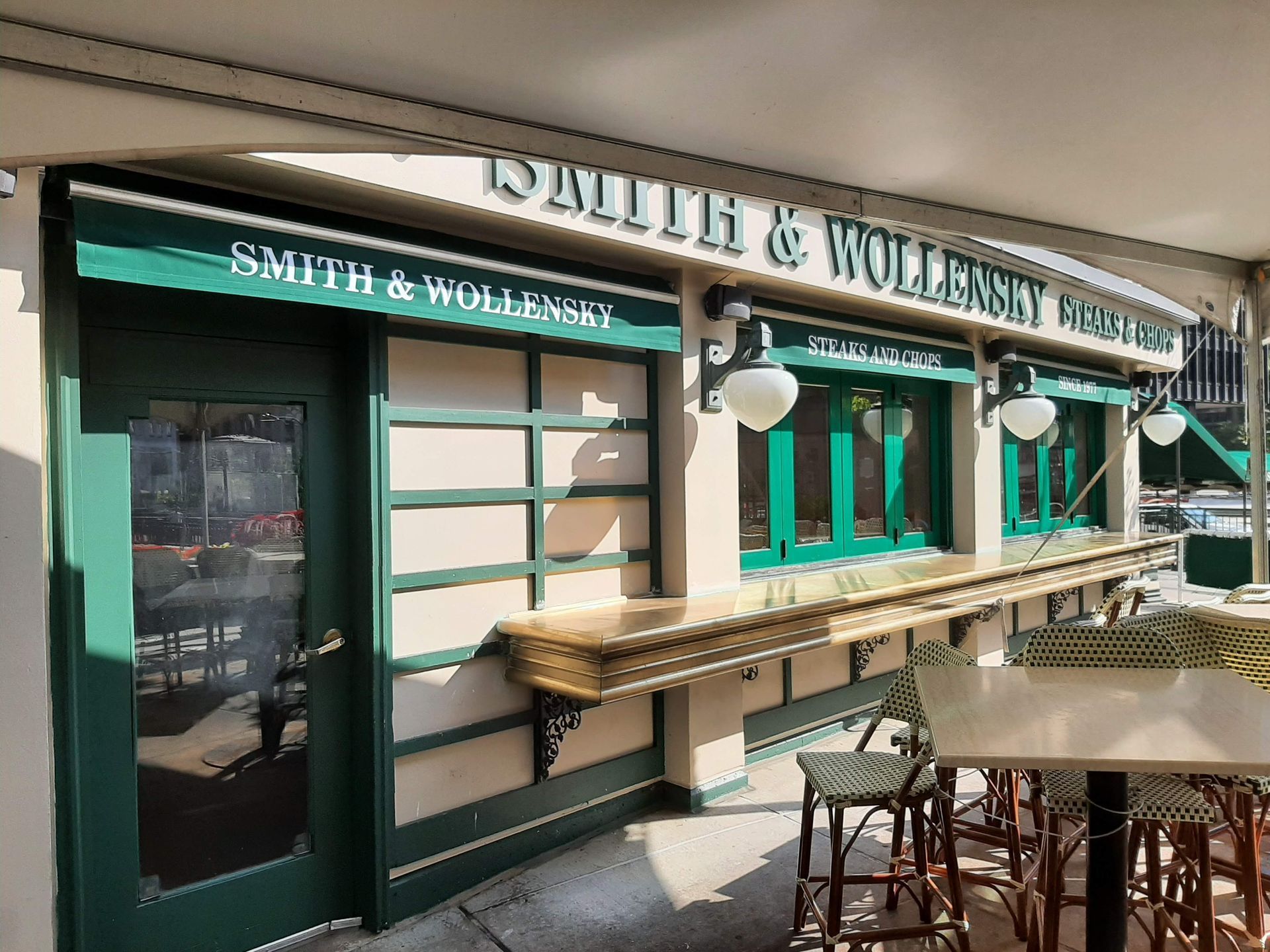 A green and white building with tables and chairs in front of it.