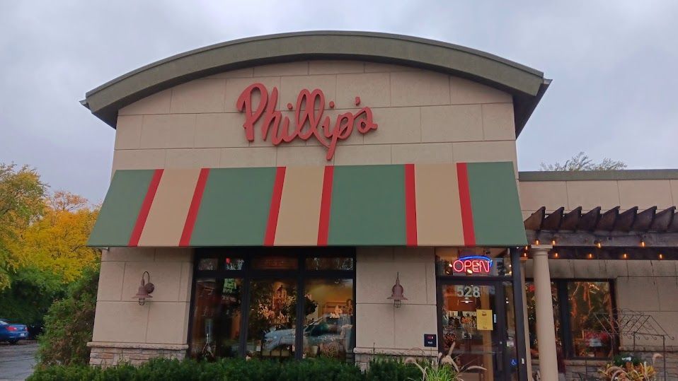 The front of a phillips restaurant with a green awning.
