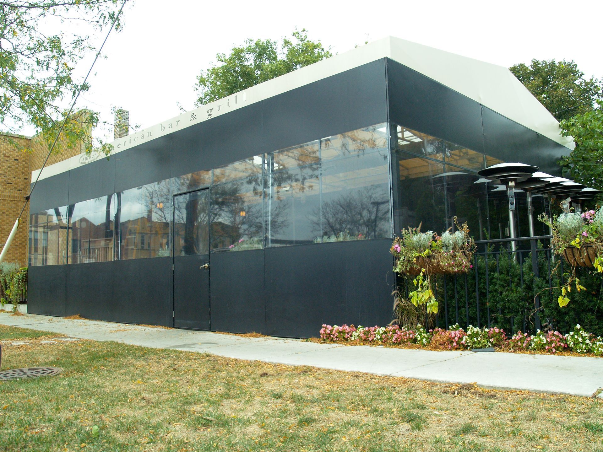 A large black building with a white roof is sitting in the middle of a grassy field.