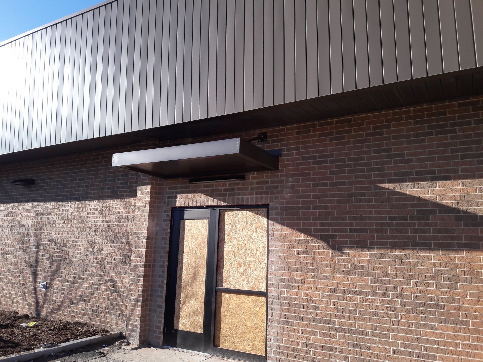 A brick building with a door that is boarded up