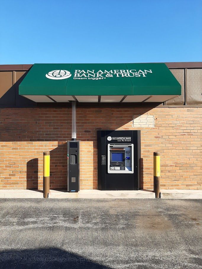 A green awning over an atm machine in front of a brick building.