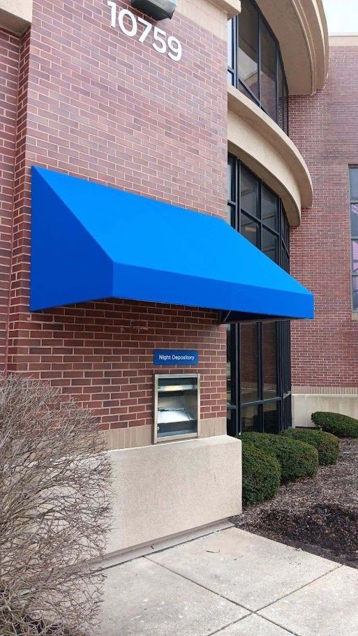 A blue awning is on the side of a brick building.