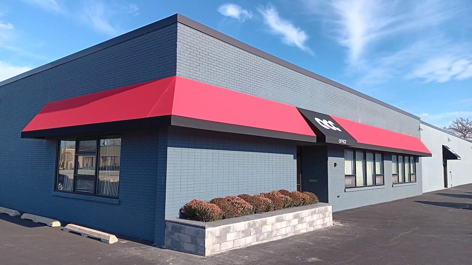 A gray building with a red awning on the side