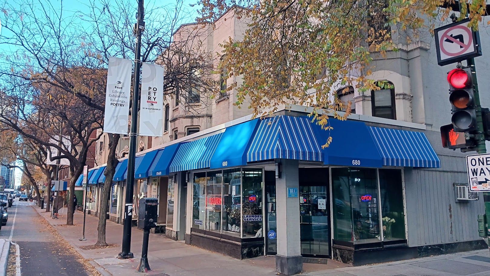 A store with blue awnings is on the corner of a street