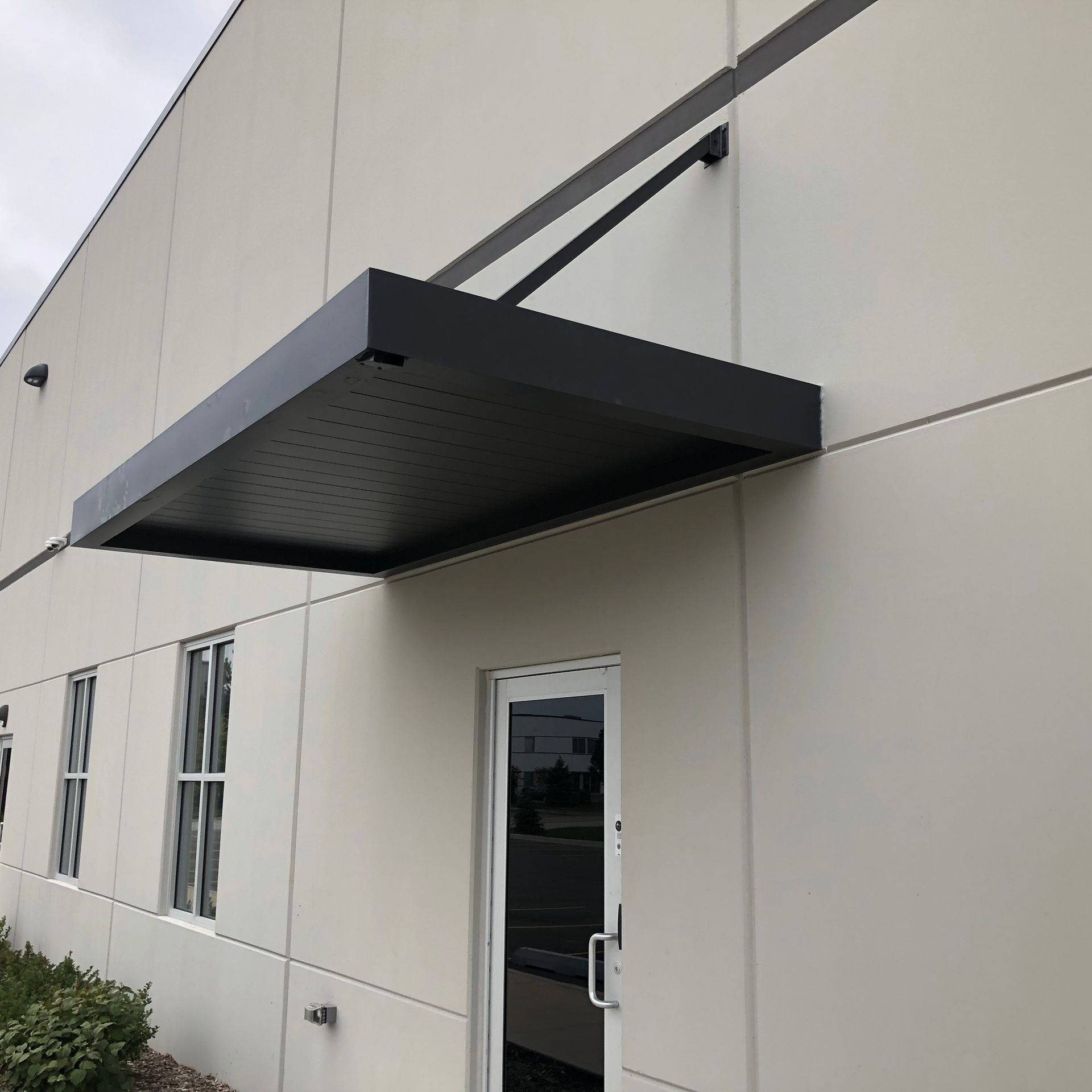 A white building with a black canopy over the door