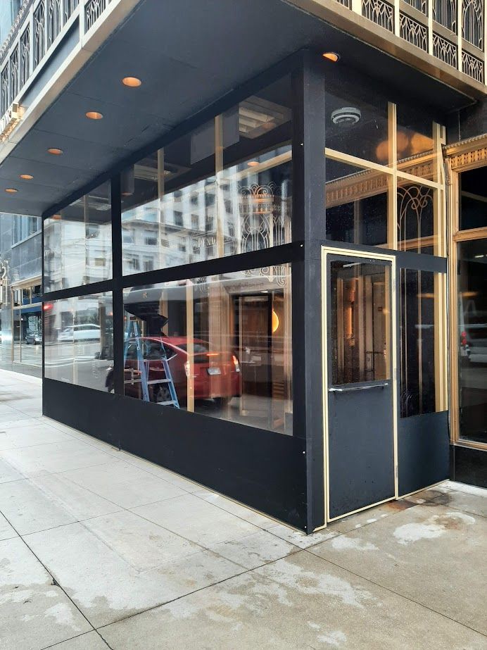 A building with a lot of windows and a red car parked in front of it.