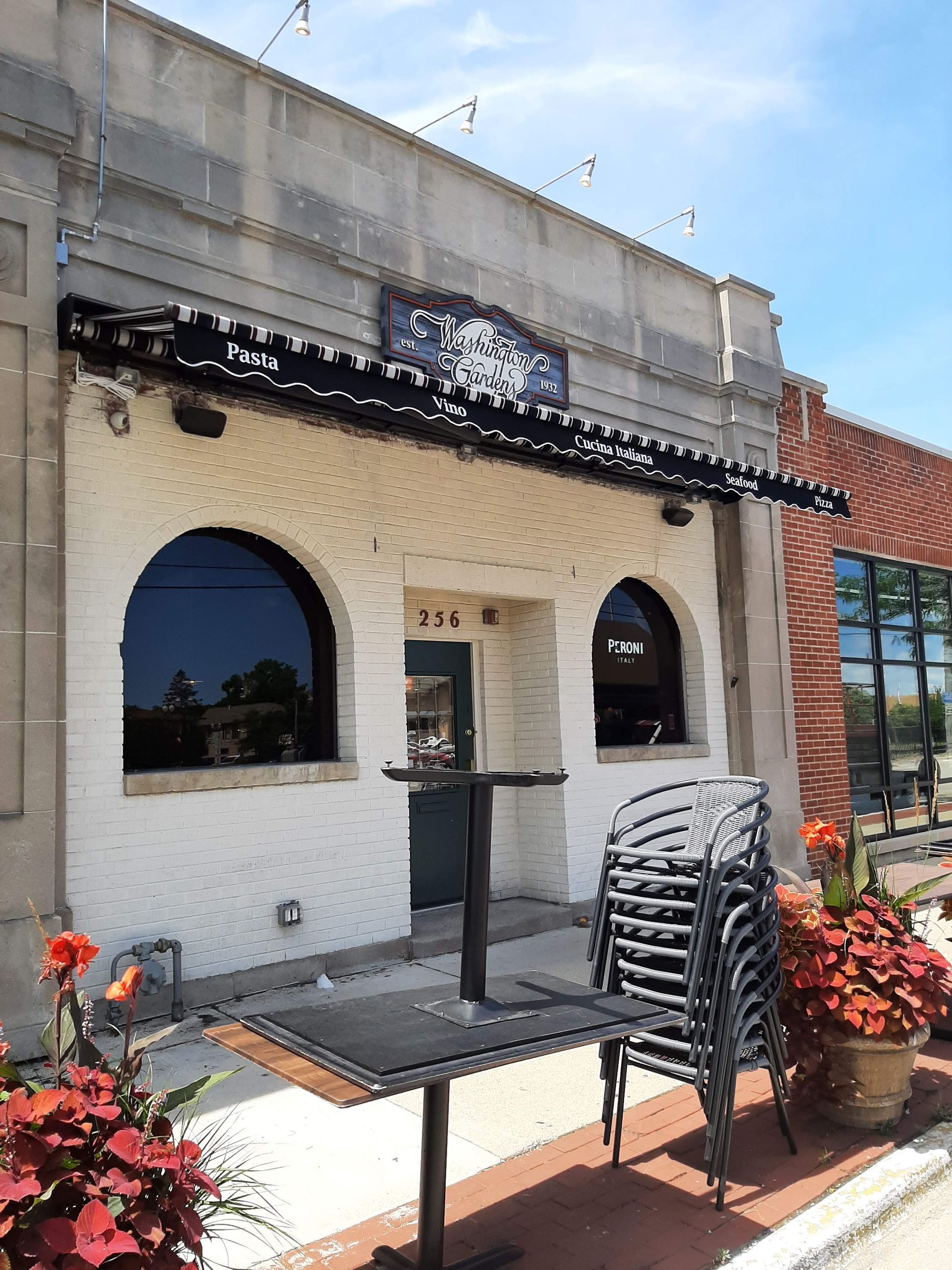 A white building with a black awning and a stack of chairs in front of it