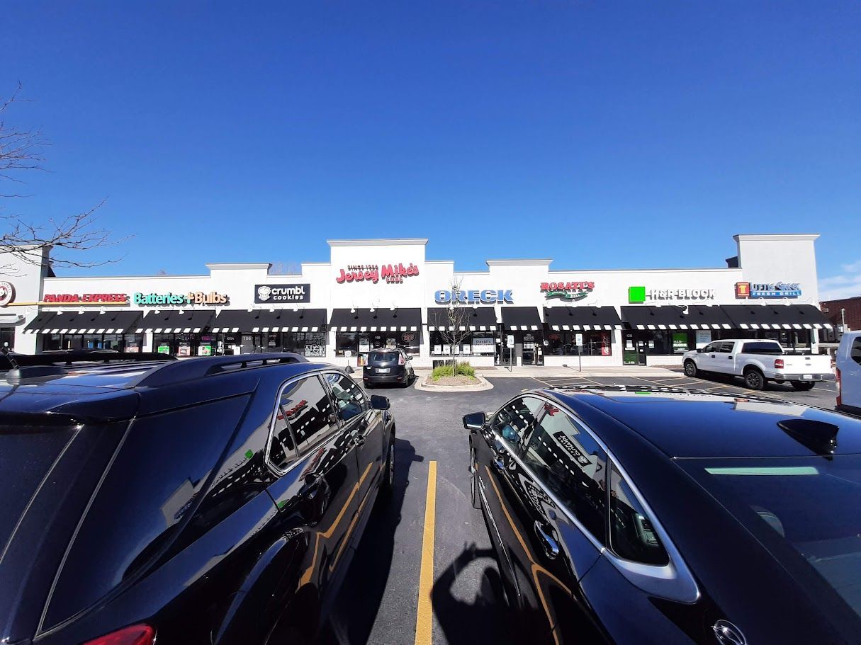 A lot of cars are parked in front of a shopping center
