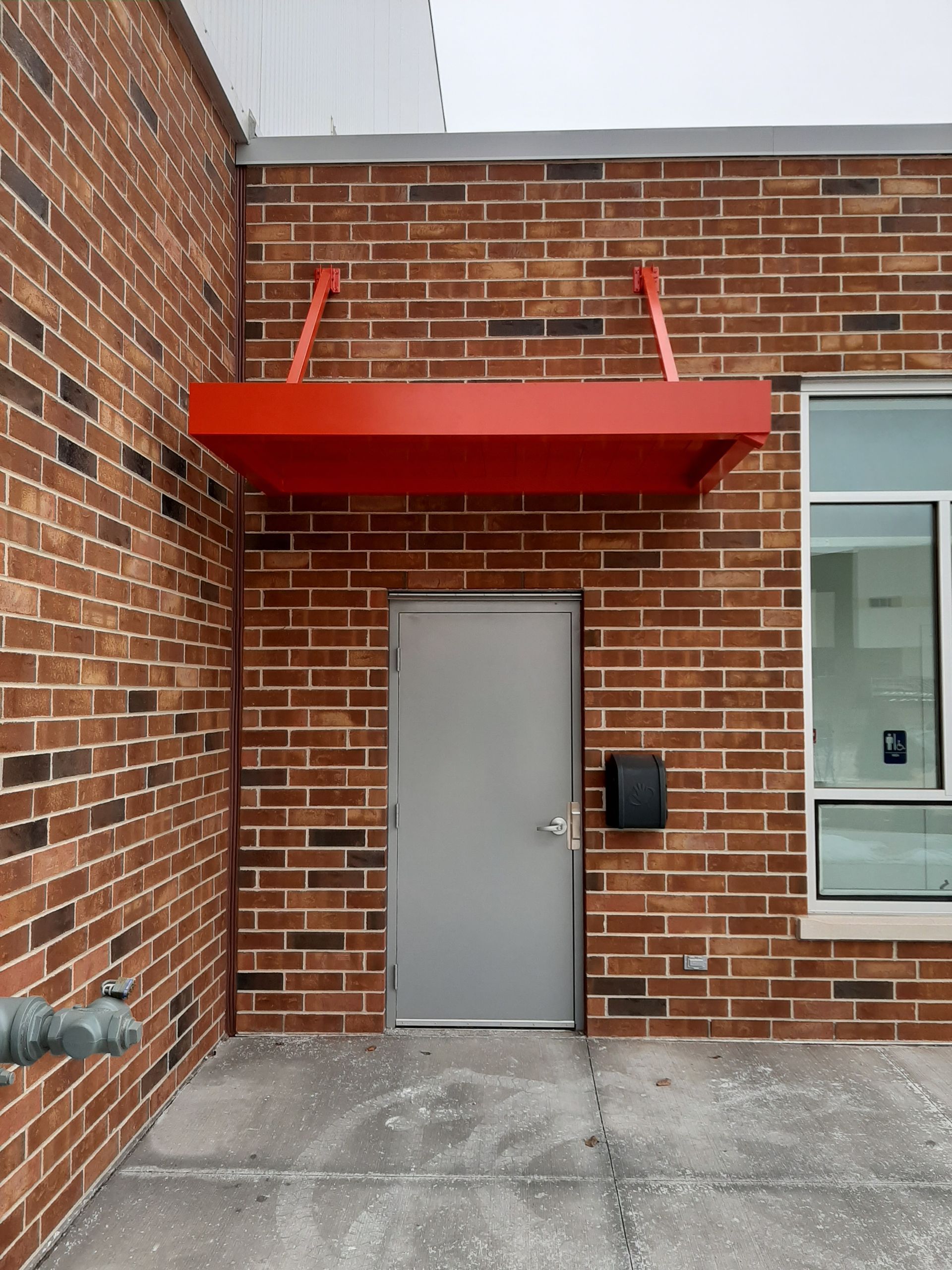A brick building with a red canopy over a door.
