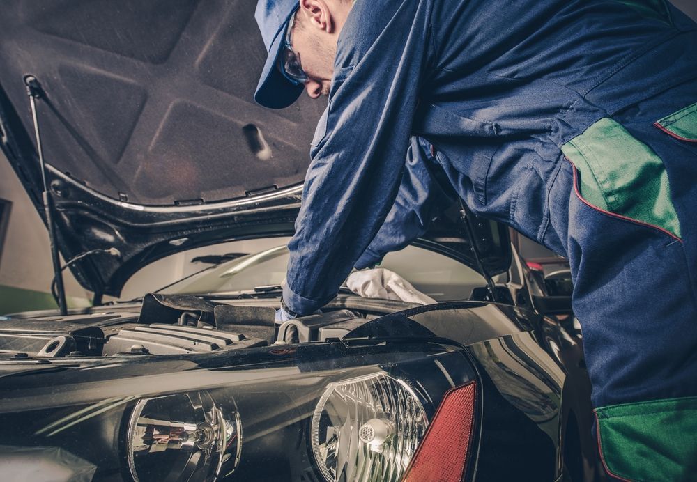 A Man is Adjusting a Cars Wheels in a Garage — Bowral Auto Care In Mittagong, NSW