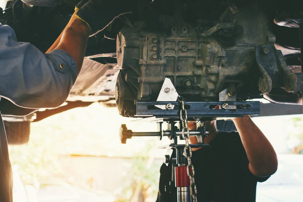 A Man Is Working On A Car Engine On A Lift — Bowral Auto Care In Mittagong, NSW