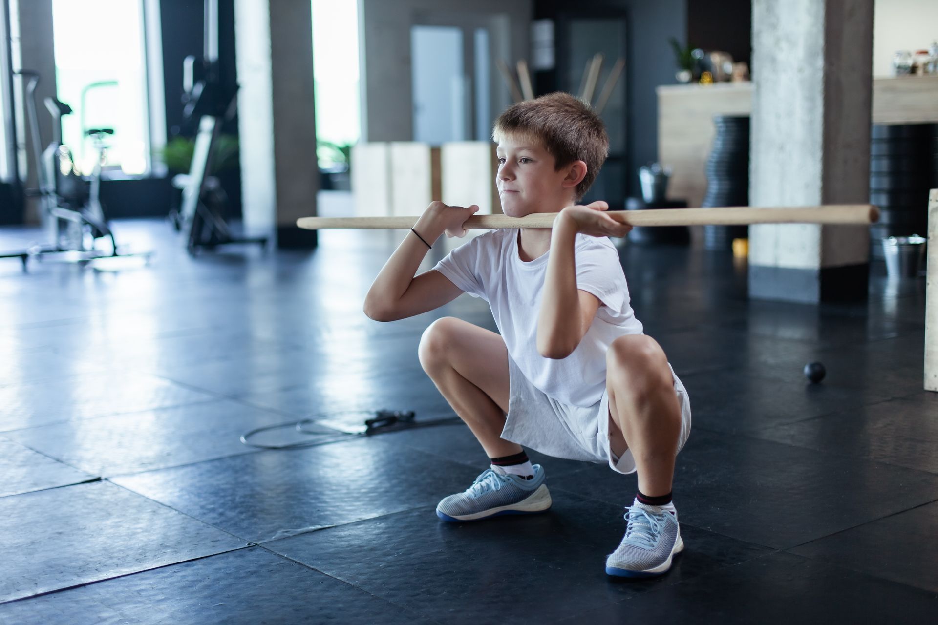 Trainer assisting person doing crunches on a blue floor in a gym.