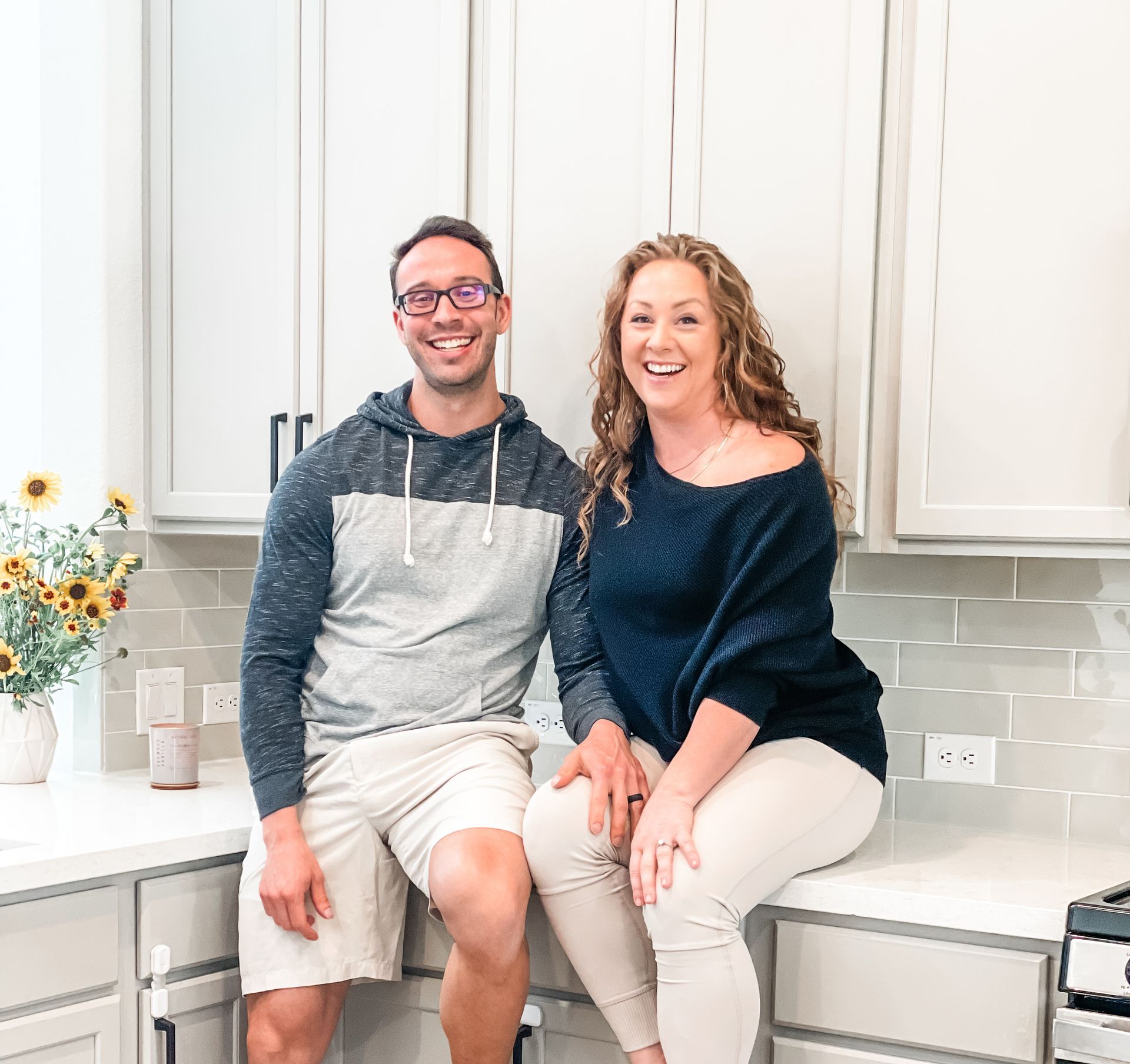Owners of AP Digital Service Peter & Amanda are sitting on a counter in a kitchen.